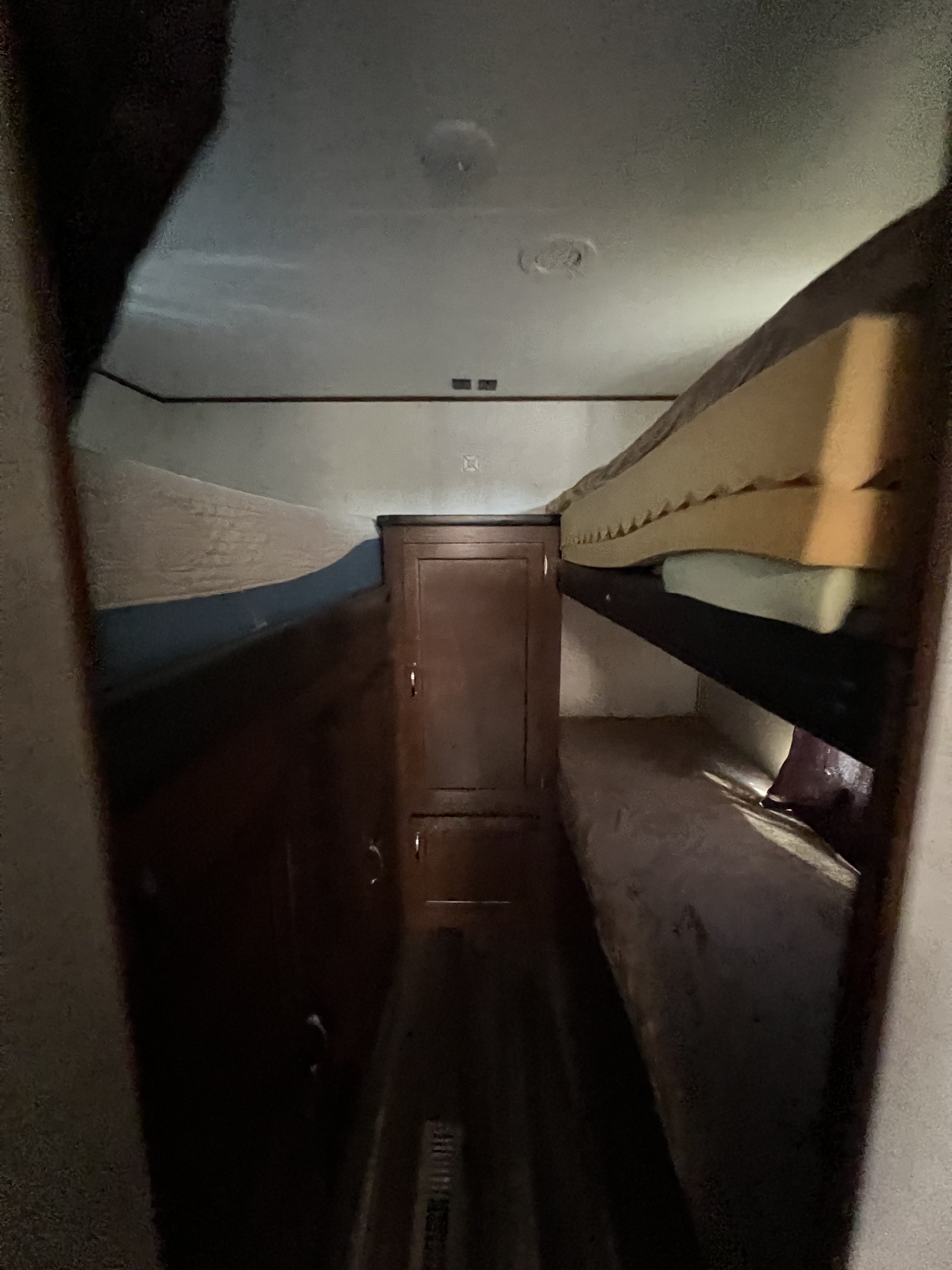View down a narrow RV rental corridor, showcasing bunk beds on both sides and a central wardrobe for compact living.. Jayco Jay Flight 2017