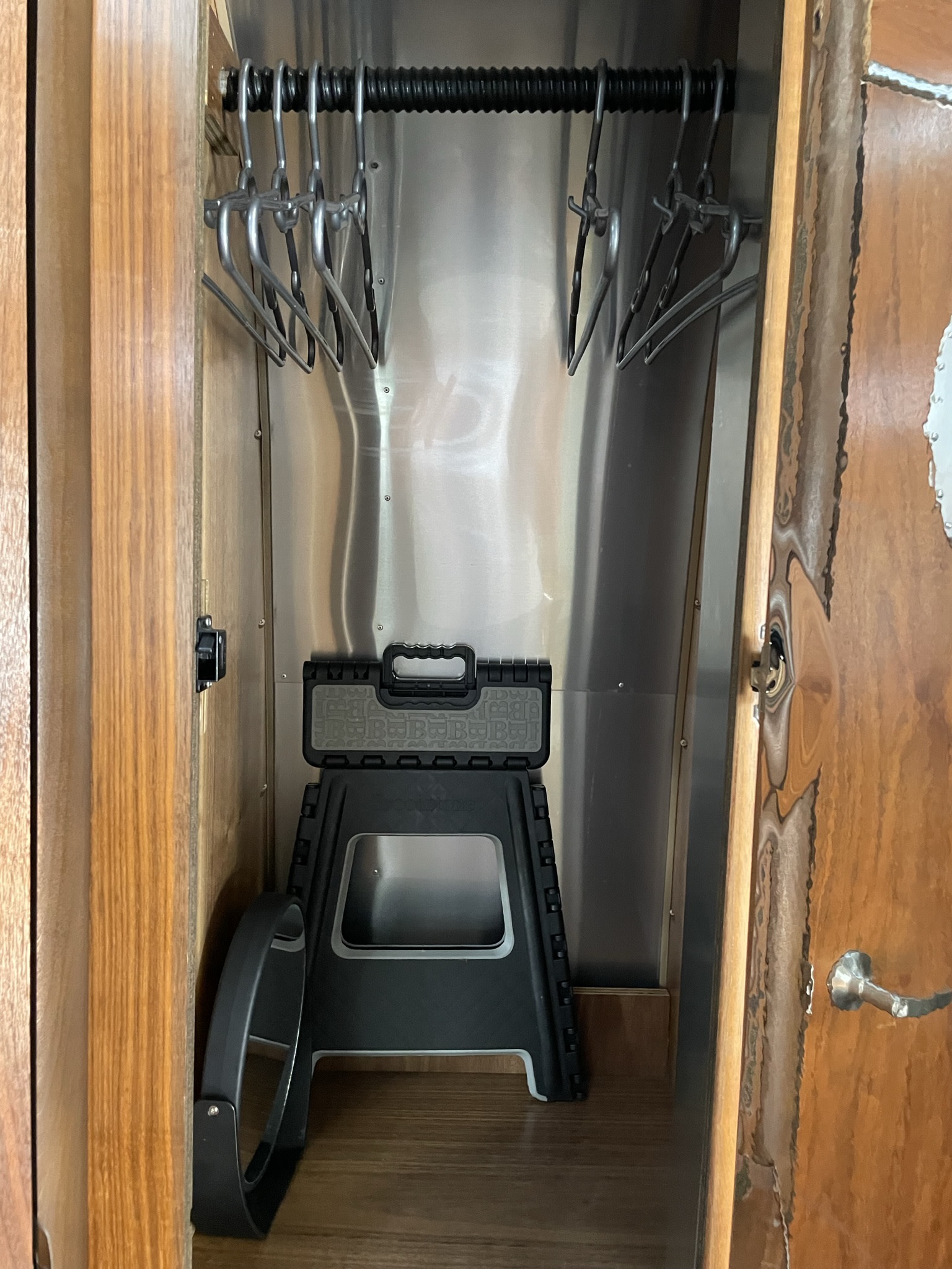 Compact RV rental closet with space-saving hangers & step stool, featuring a sleek metal and wood interior for travel.. Airstream International 2007