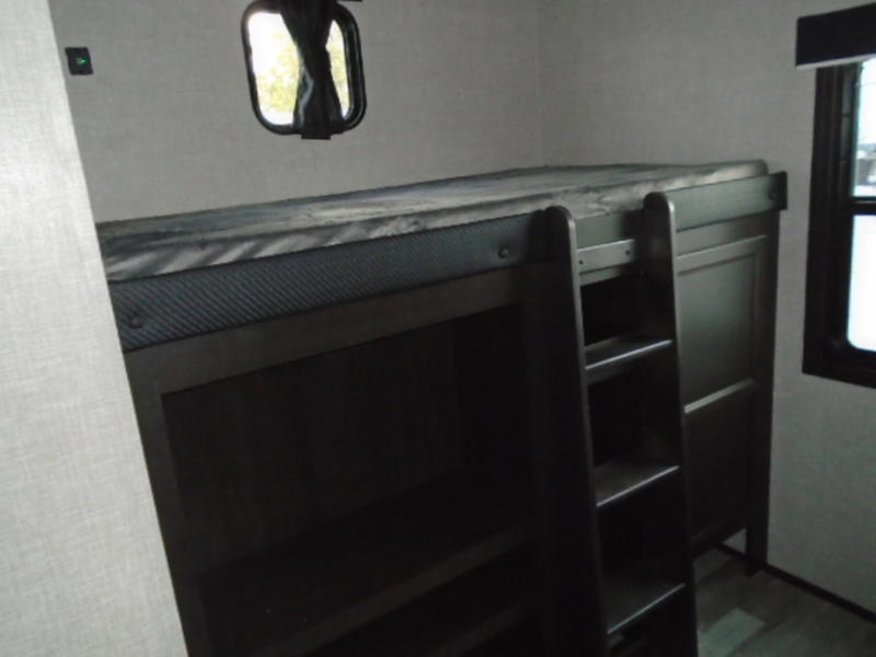 RV rental bunk beds with a ladder in a compact interior. A window and light are visible, offering functional sleeping space.. Jayco Jay Flight 2023