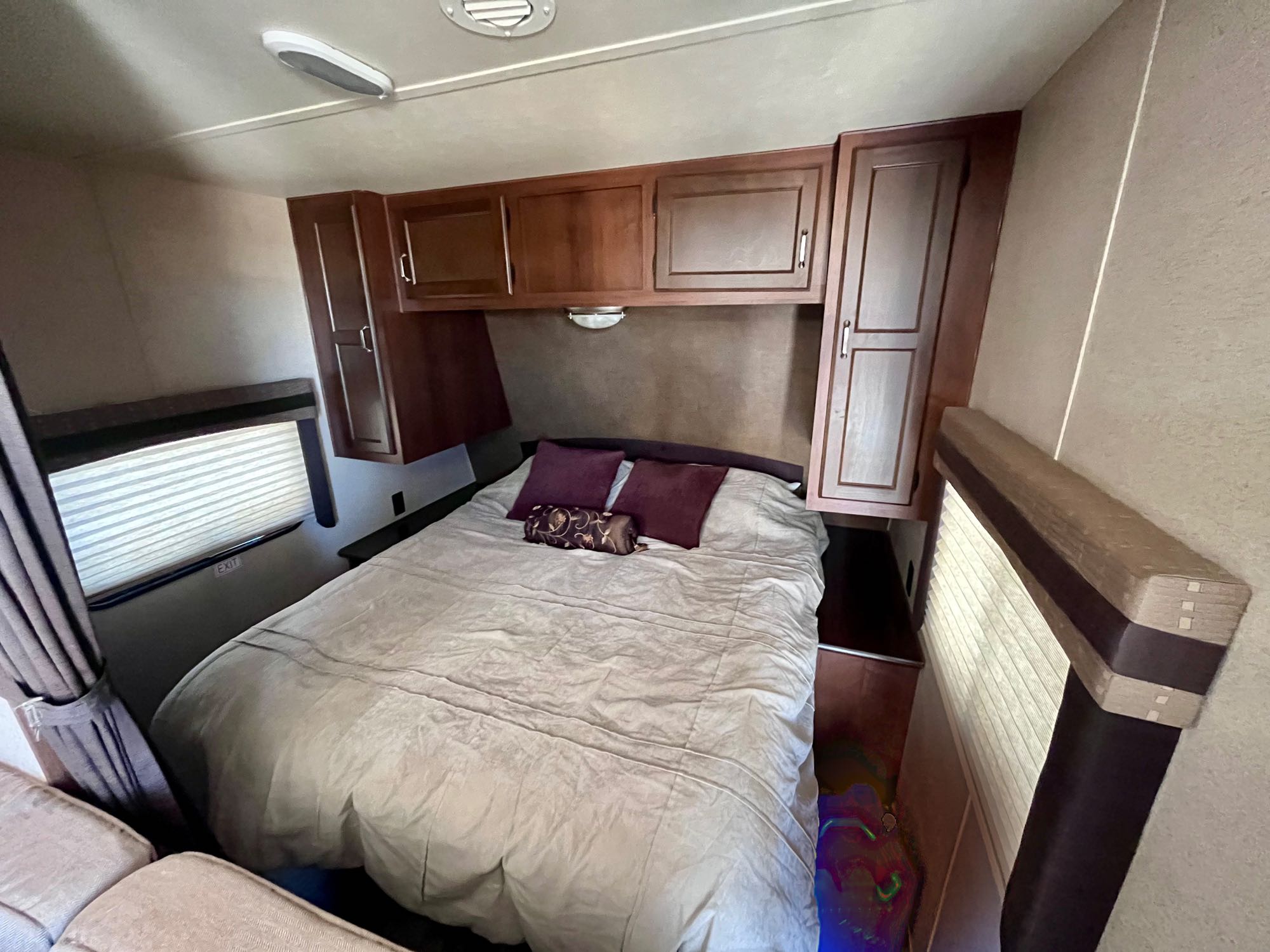 Step into this RV rental's well-appointed bedroom, featuring a large bed, ample storage cabinets, and bright windows.. Jayco Jay Flight 2015