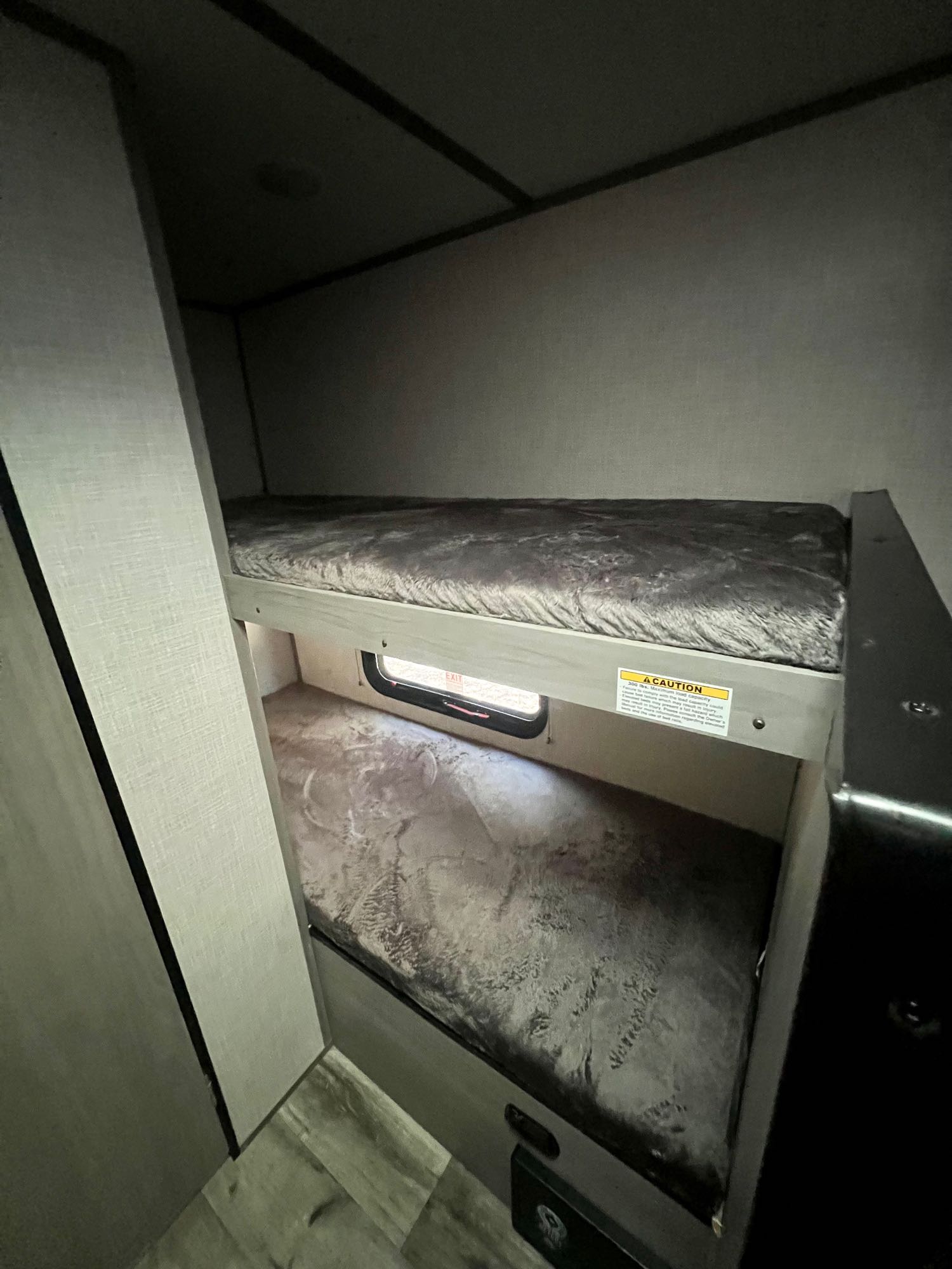RV rental bunk beds: Cozy, stacked sleeping area inside a modern camper, featuring soft bedding and a lower exit window.. Dutchmen Coleman Lantern LT 2023