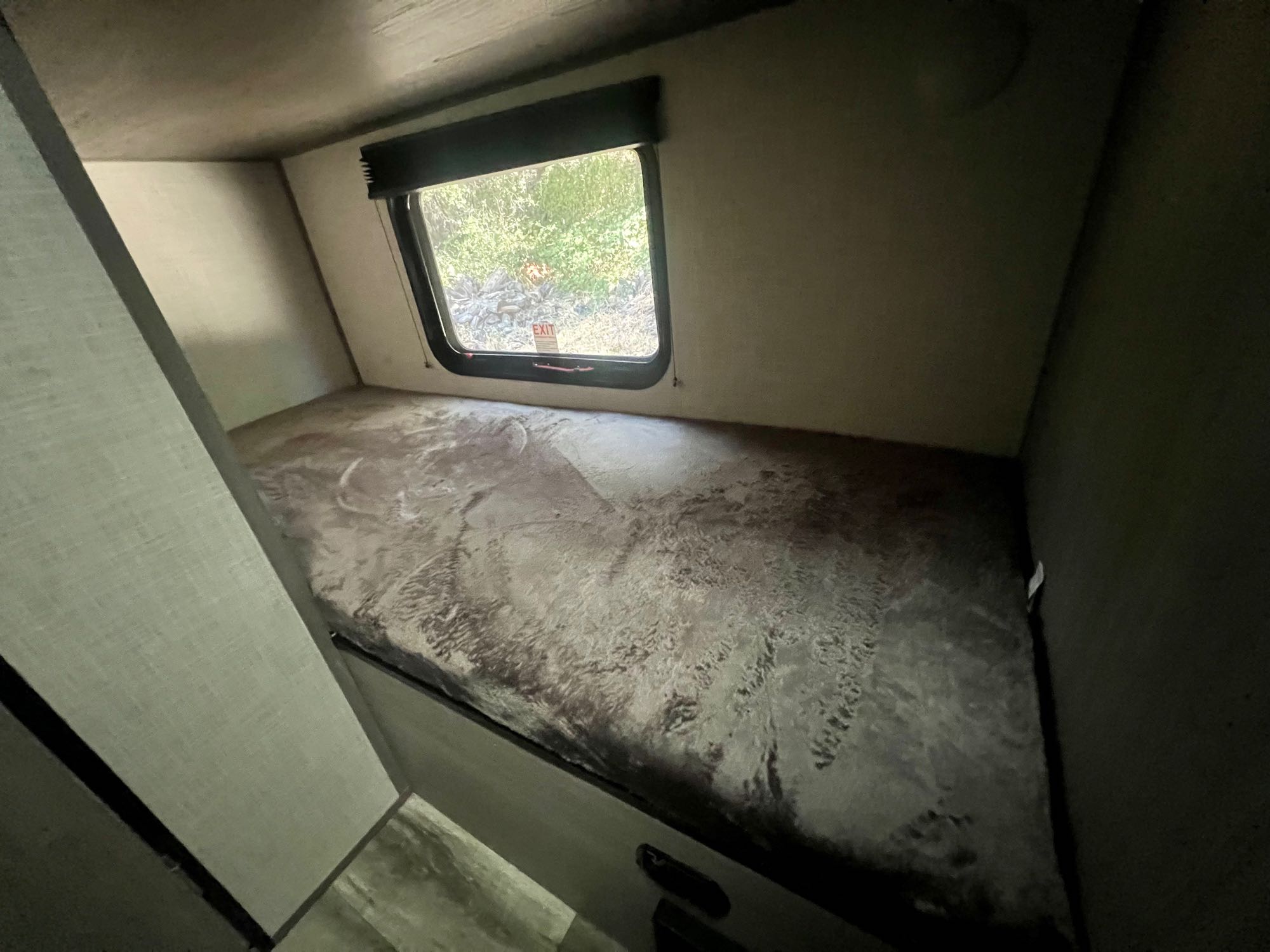 RV rental: Interior view of a cozy bunk bed with a window looking out at green foliage. Great for family trips!. Dutchmen Coleman Lantern LT 2023