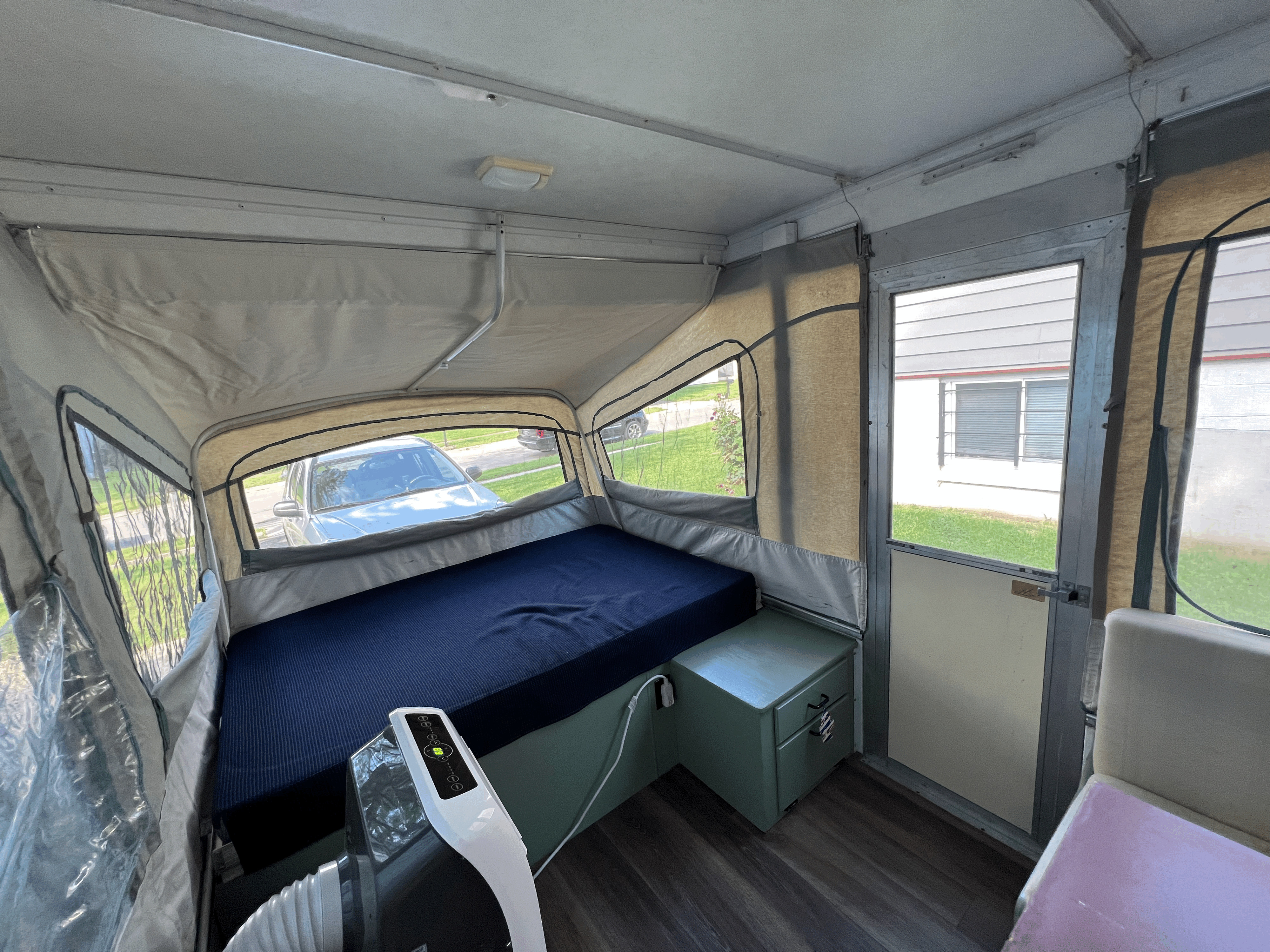 Spacious pop-up RV rental interior with bed, portable AC, and outdoor views for comfortable camping.. Coleman Destiny Cedar 1992