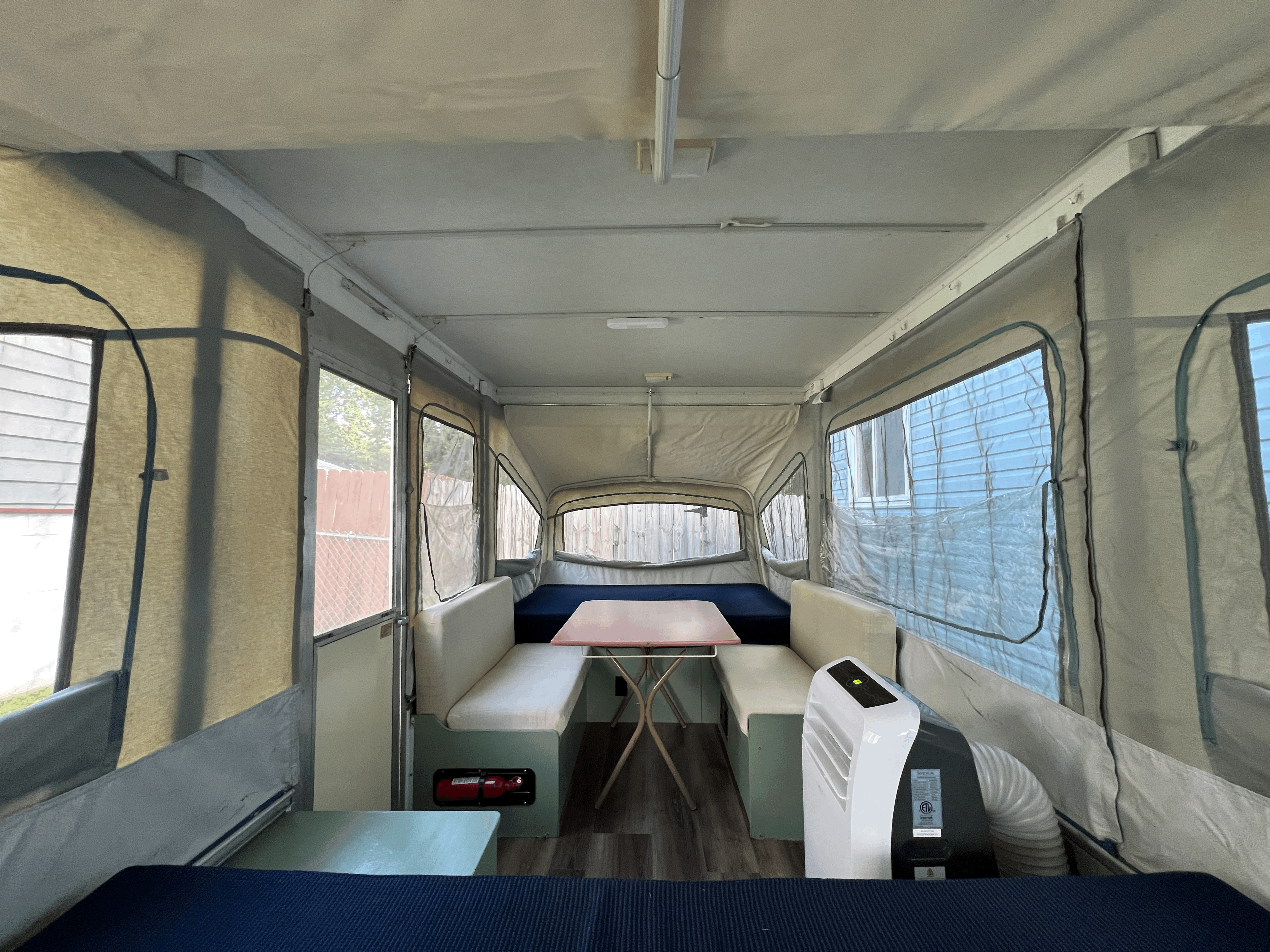 Pop-up camper RV rental interior showing a dinette, sleeping areas, and a portable AC for comfortable camping.. Coleman Destiny Cedar 1992