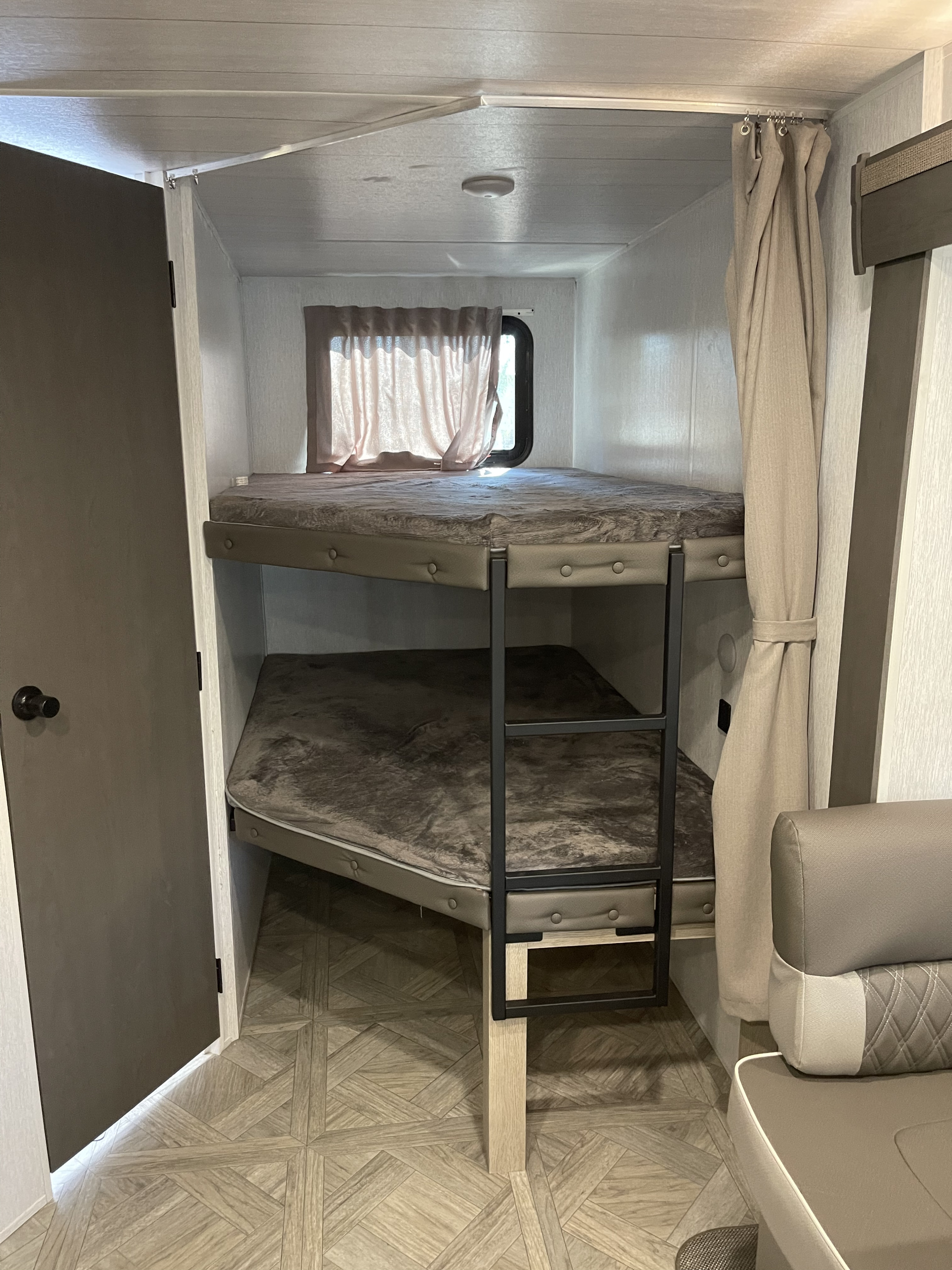 Cozy RV rental bunk beds with soft bedding, a ladder, and a window for comfortable sleeping in a compact space.. Other Other 2024
