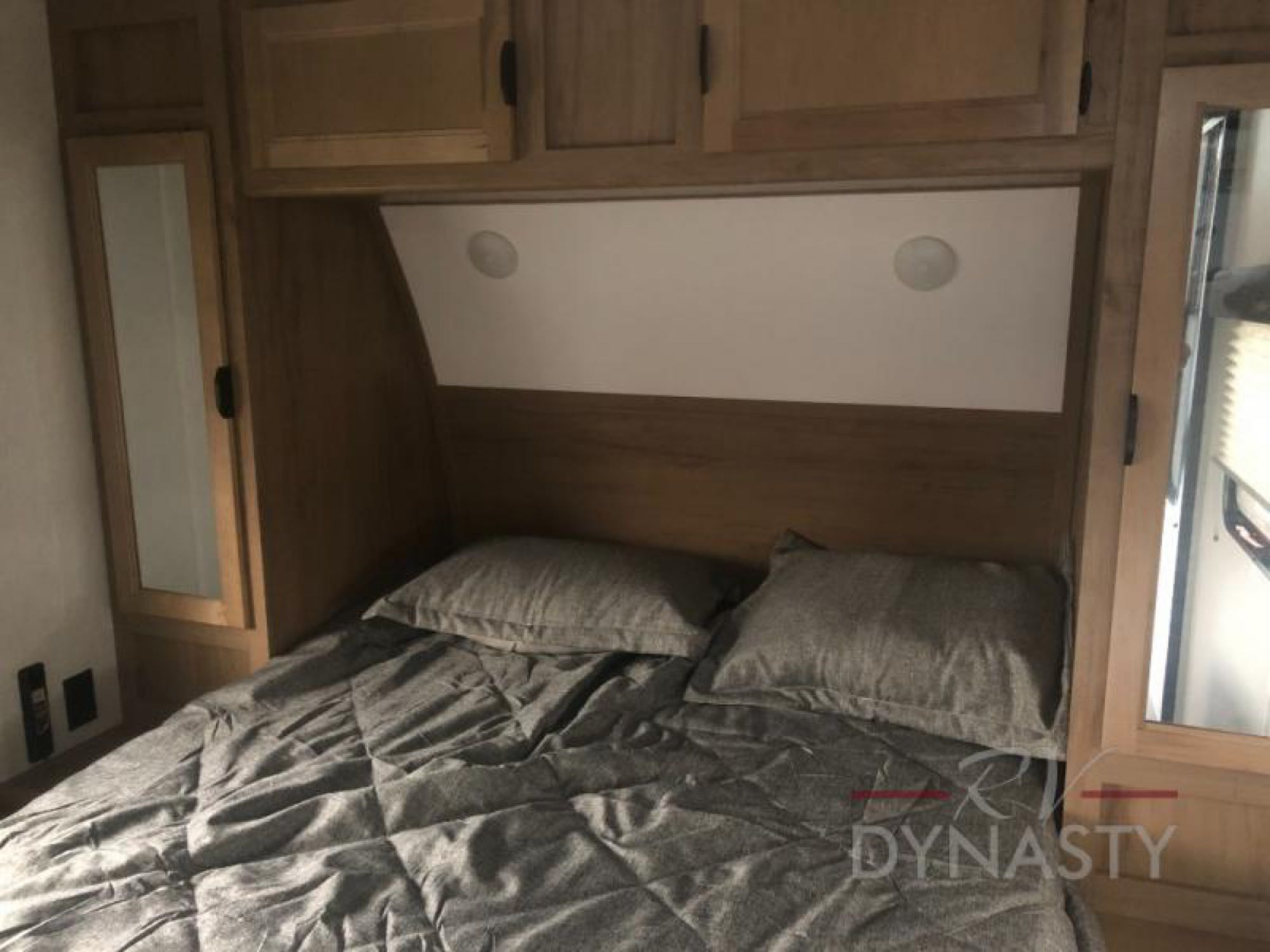 Comfortable RV rental bedroom featuring a bed, gray bedding, mirrored cabinets, and practical overhead lighting.. Forest River Cherokee Grey Wolf 2024