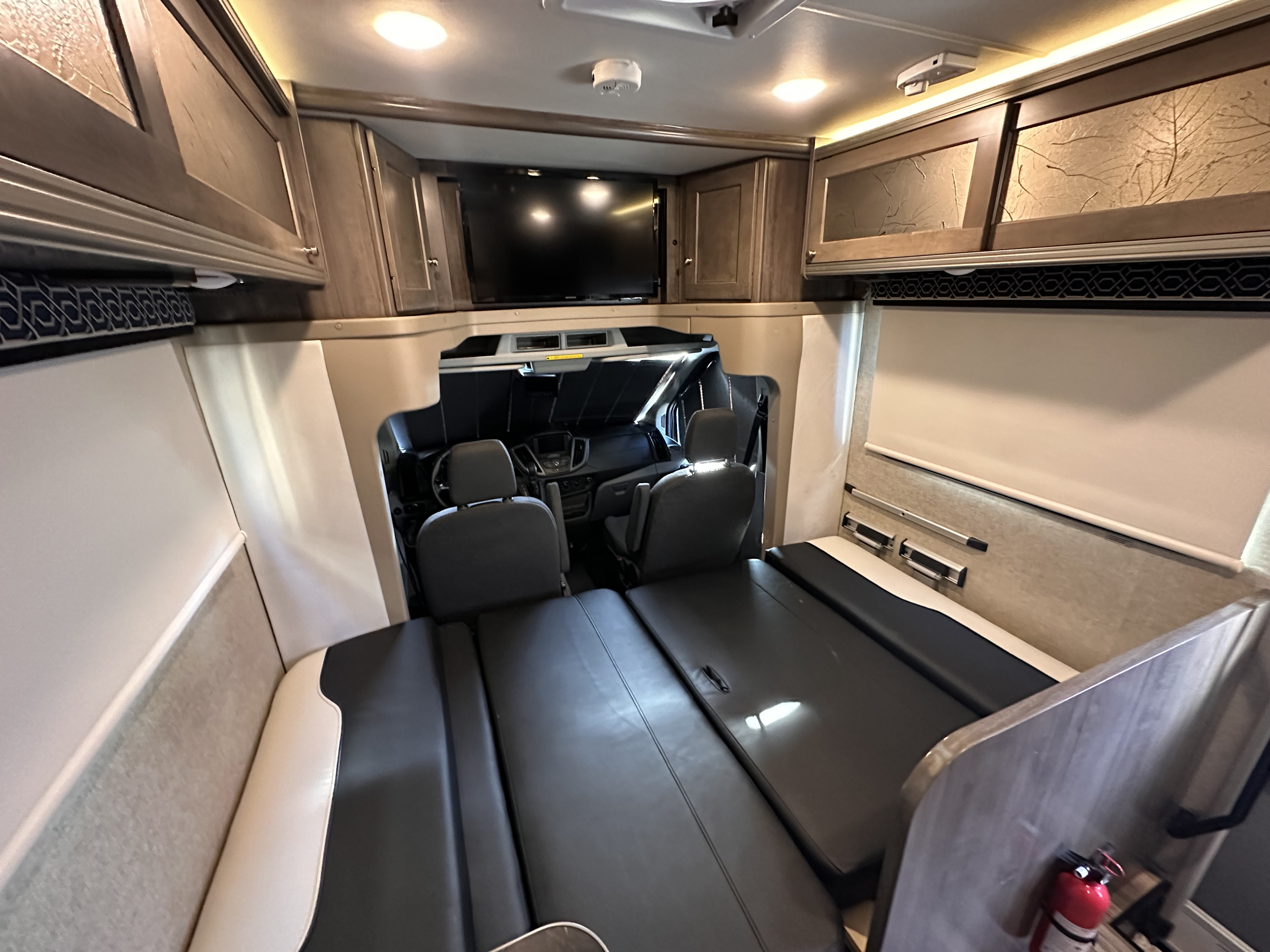 Modern RV rental interior with captain's chairs, convertible beds, overhead storage, and TV, designed for comfortable adventures.. Winnebago Fuse 2017