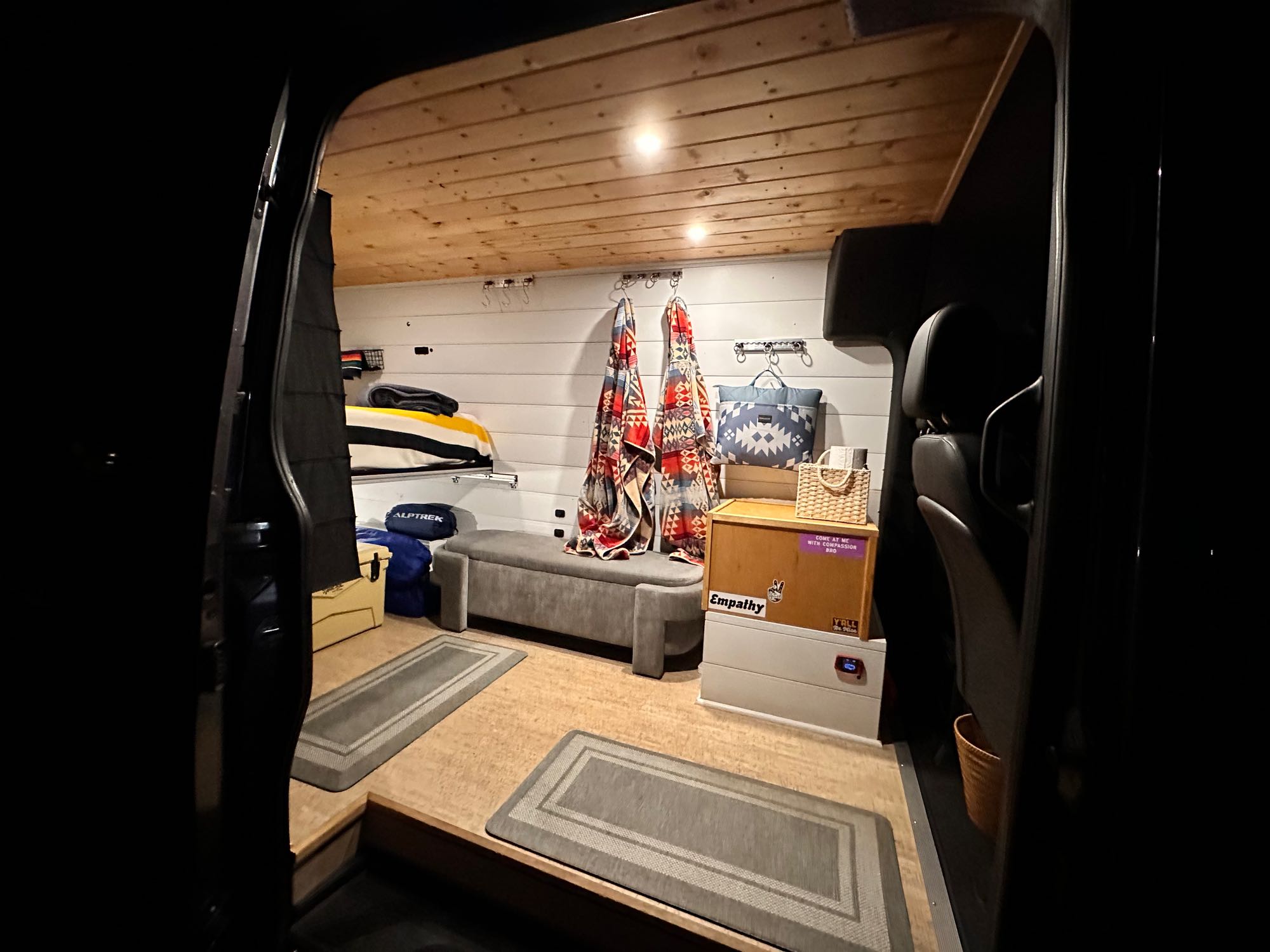 Cozy RV rental interior: A well-appointed camper van with wooden ceiling, shiplap walls, and organized storage for road trips.. Mercedes-Benz Sprinter 2020