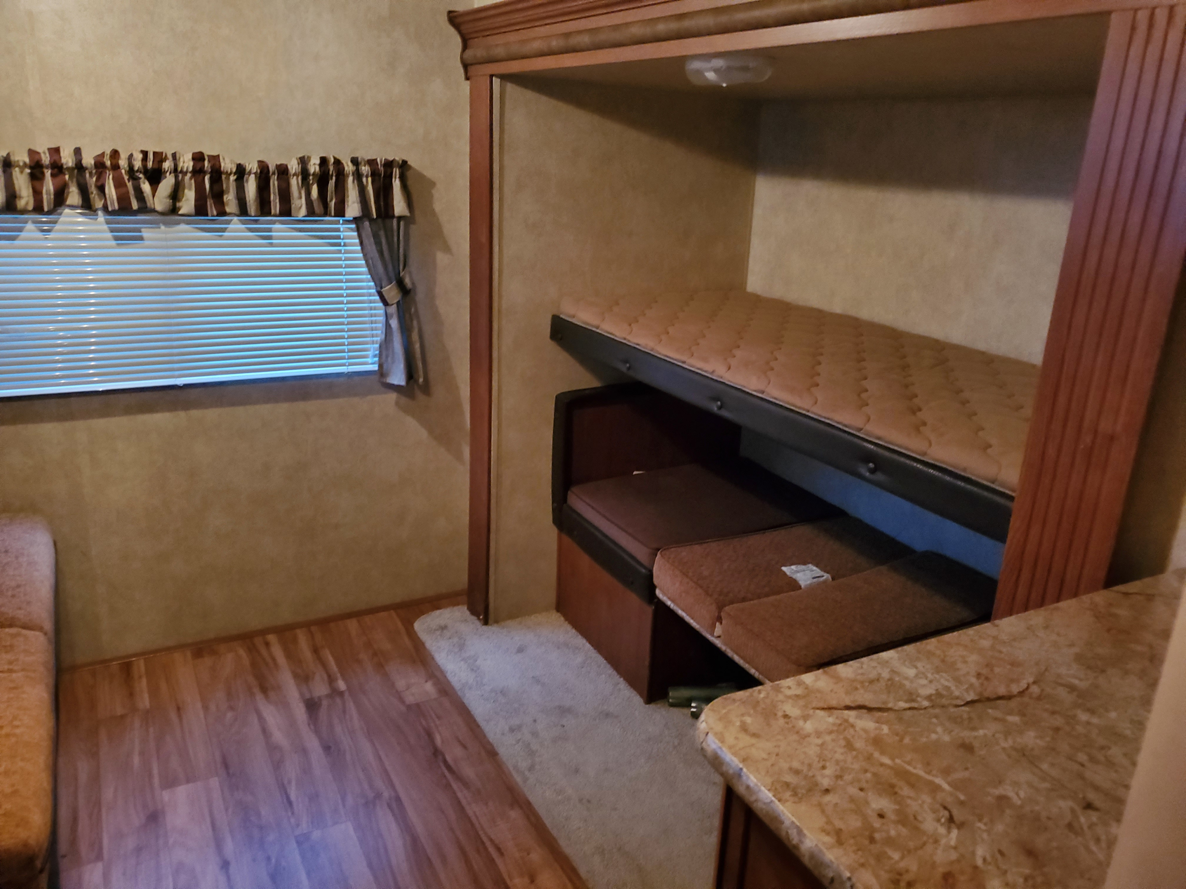 RV rental interior: cozy bunk beds, window with blinds, and seating. Ideal for camper adventures.. Forest River Salem 2014