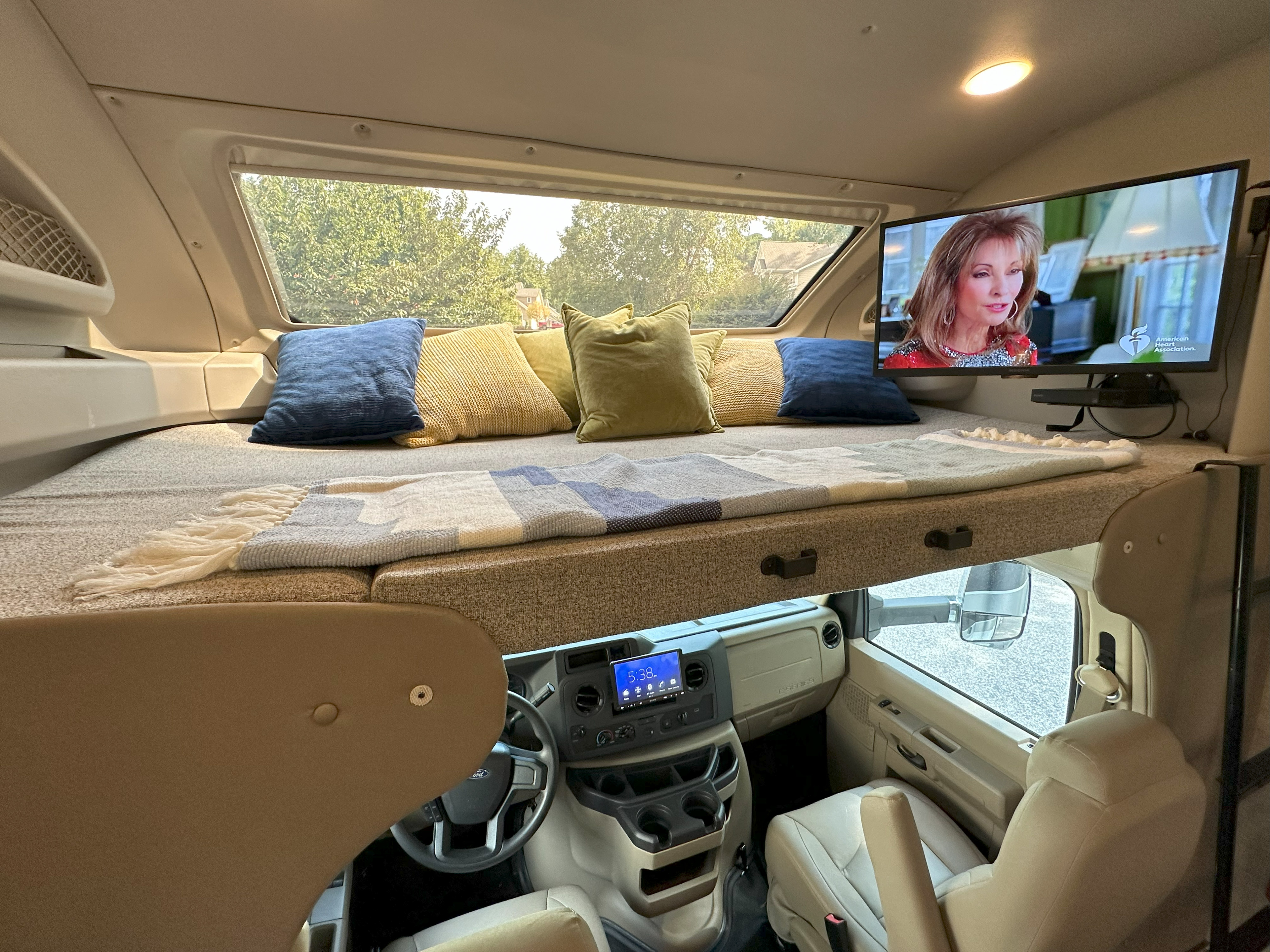 Experience comfort in this RV rental featuring an overhead bed with pillows, TV, and glimpse of the driver's cabin below.. Entegra Coach Esteem 2021