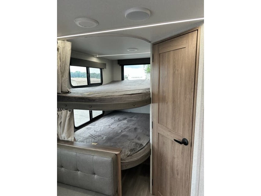 RV rental interior features bunk beds with windows, providing comfortable sleeping space.. Grand Design Imagine XLS 2023