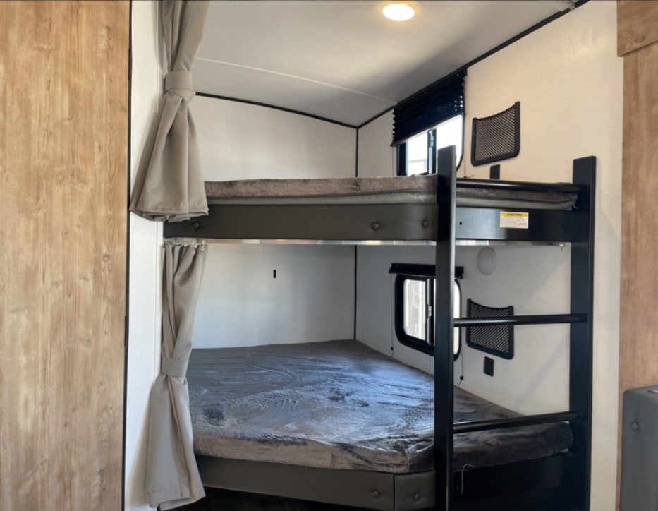 Inside this rv rental, cozy bunk beds with privacy curtains, windows, and mesh storage pockets create a comfortable sleeping area.. Keystone RV Springdale 2022
