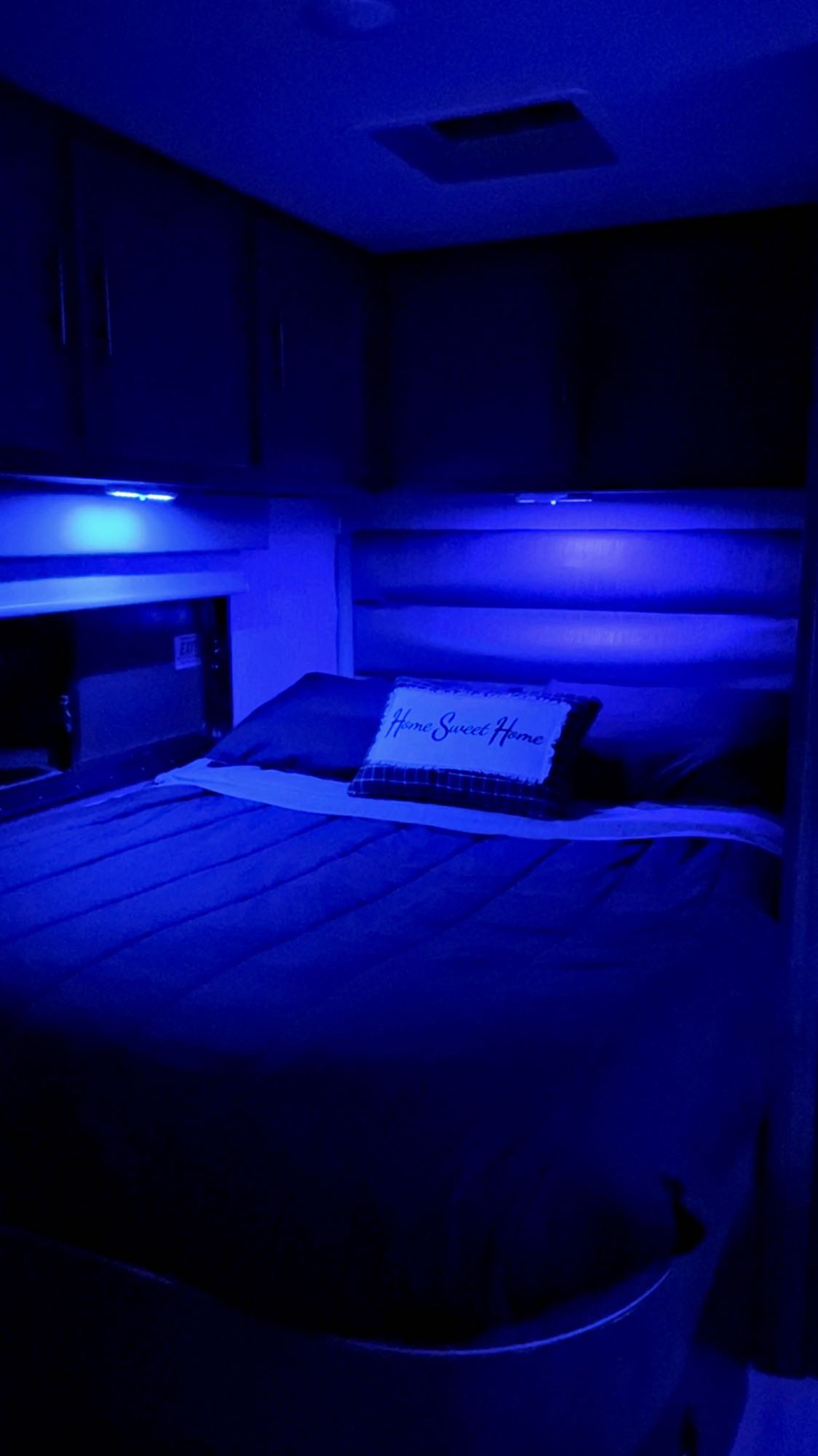 Step into comfort! This RV rental bedroom features a cozy bed with blue lighting & "Home Sweet Home" pillow.. Coachmen Prism 2023
