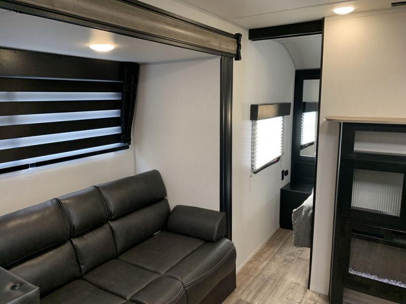 RV rental interior: Dark sofa, large window with striped blinds. View extends to a private bedroom & entertainment unit.. Forest River Cherokee Grey Wolf 2021