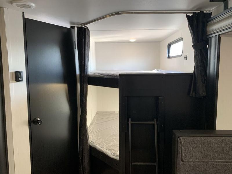 Cozy bunk beds inside an RV rental, complete with a ladder, door, and privacy curtains for a comfortable sleeping area.. Forest River Cherokee Grey Wolf 2021
