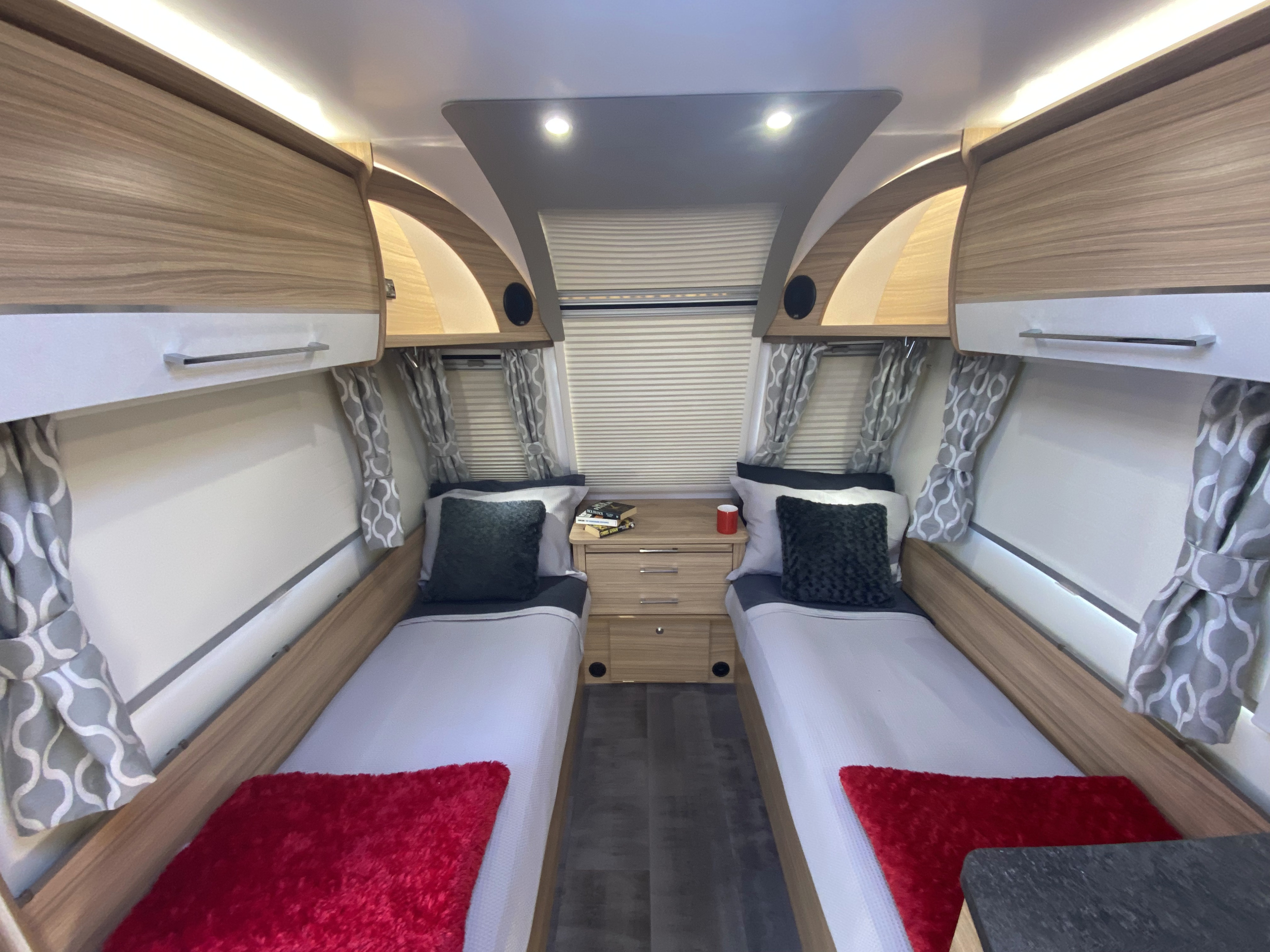 Cozy rv rental bedroom with mirrored twin beds, a central dresser, and light wood overhead cabinets.. Bailey x 2021