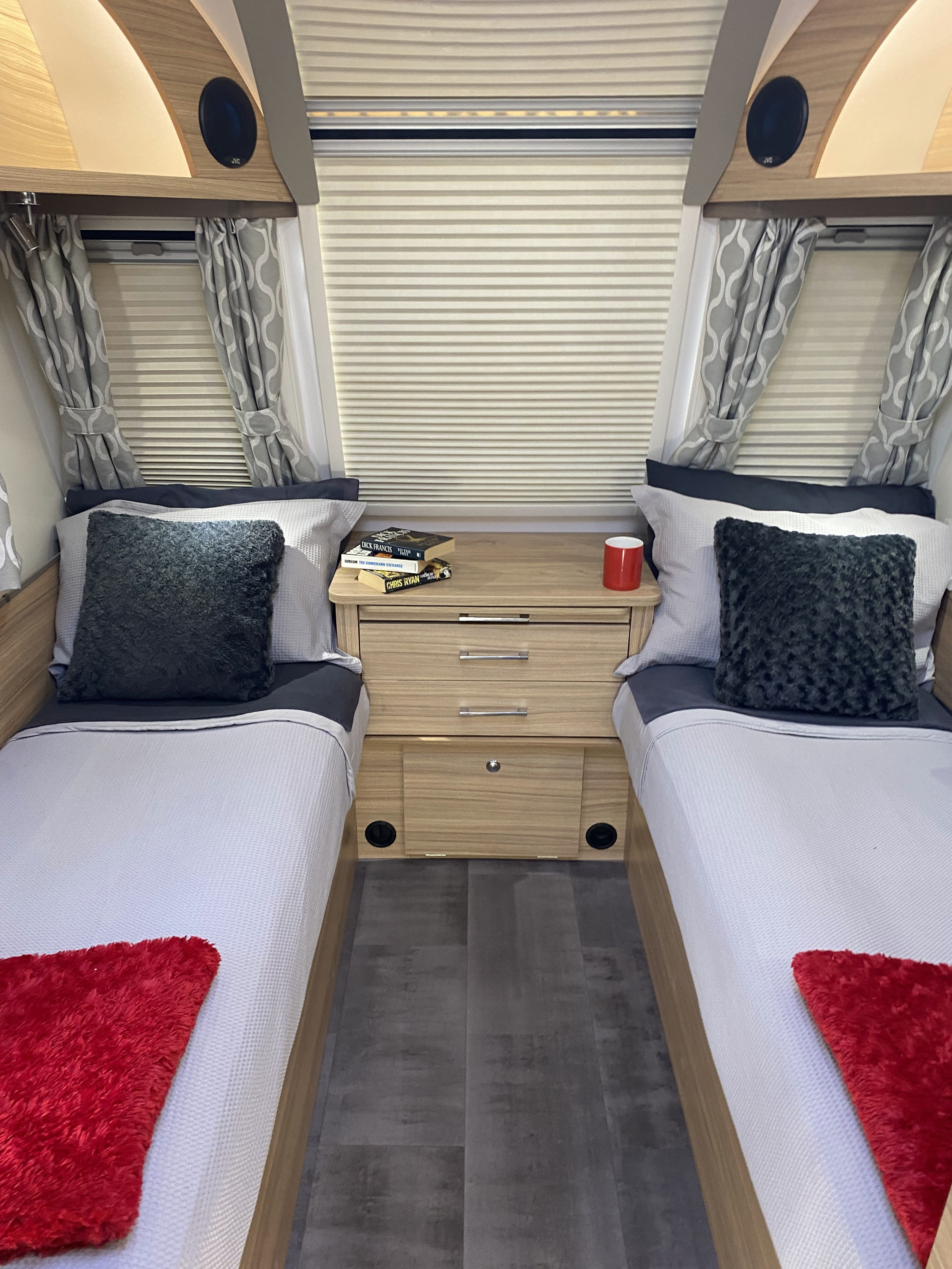 Cozy RV rental bedroom with twin beds, central nightstand, and window blinds. Light wood accents and grey bedding. Ideal for travel.. Bailey x 2021