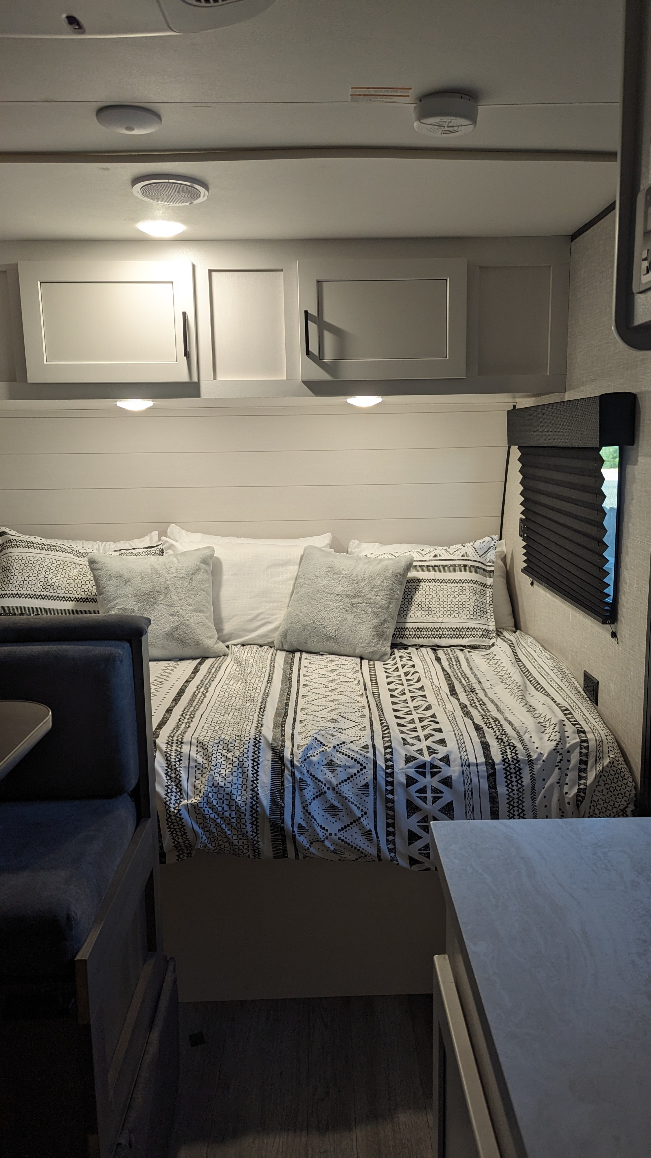 Cozy RV rental bedroom features a comfy bed with patterned linens, overhead cabinets, and soft lighting.. Jayco Jay Flight SLX 184BSW 2024