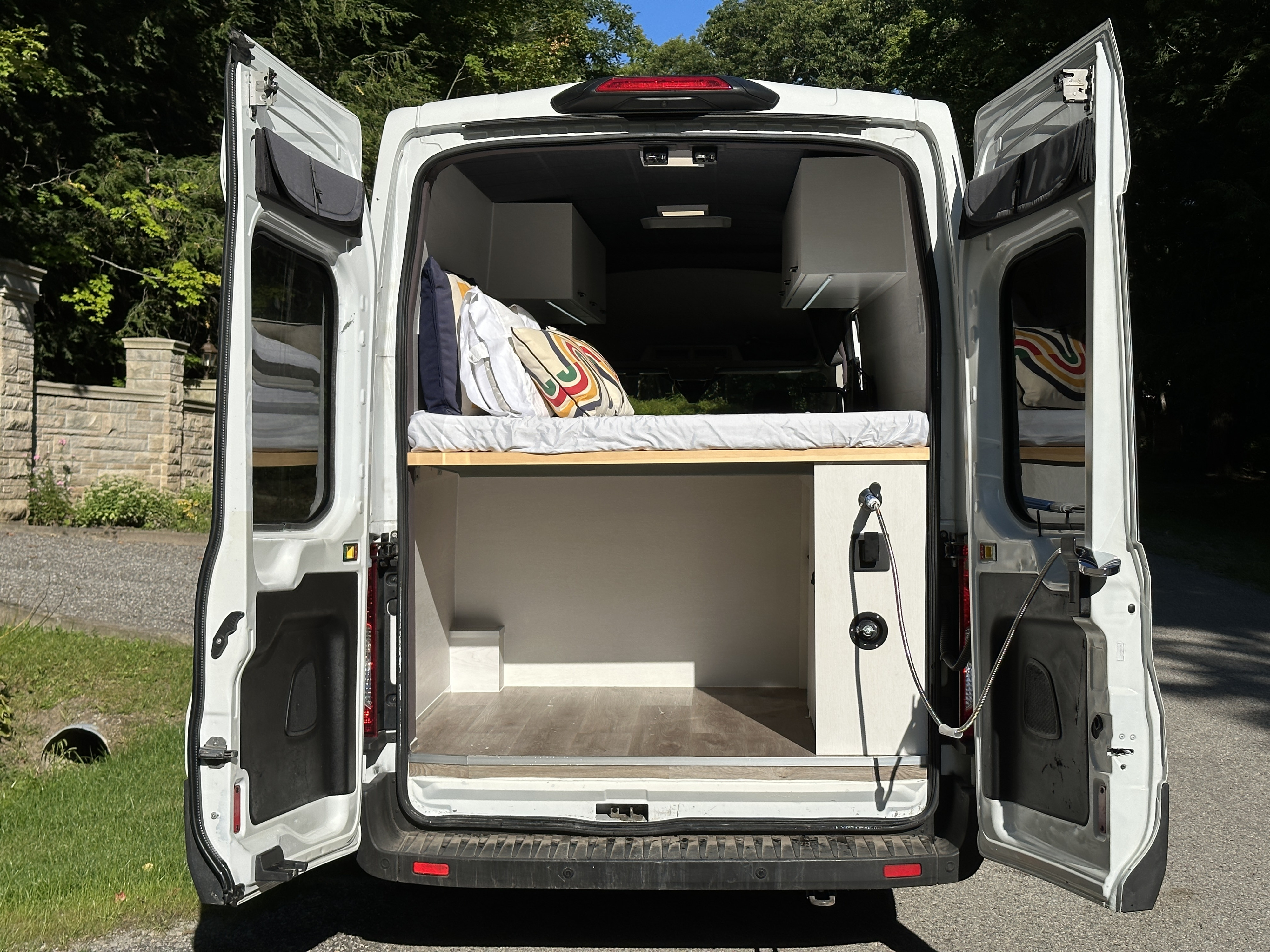 Spacious white camper van interior, perfect for RV rental adventures. Features bed, storage, and custom build.. Ford Transit T-350 2020