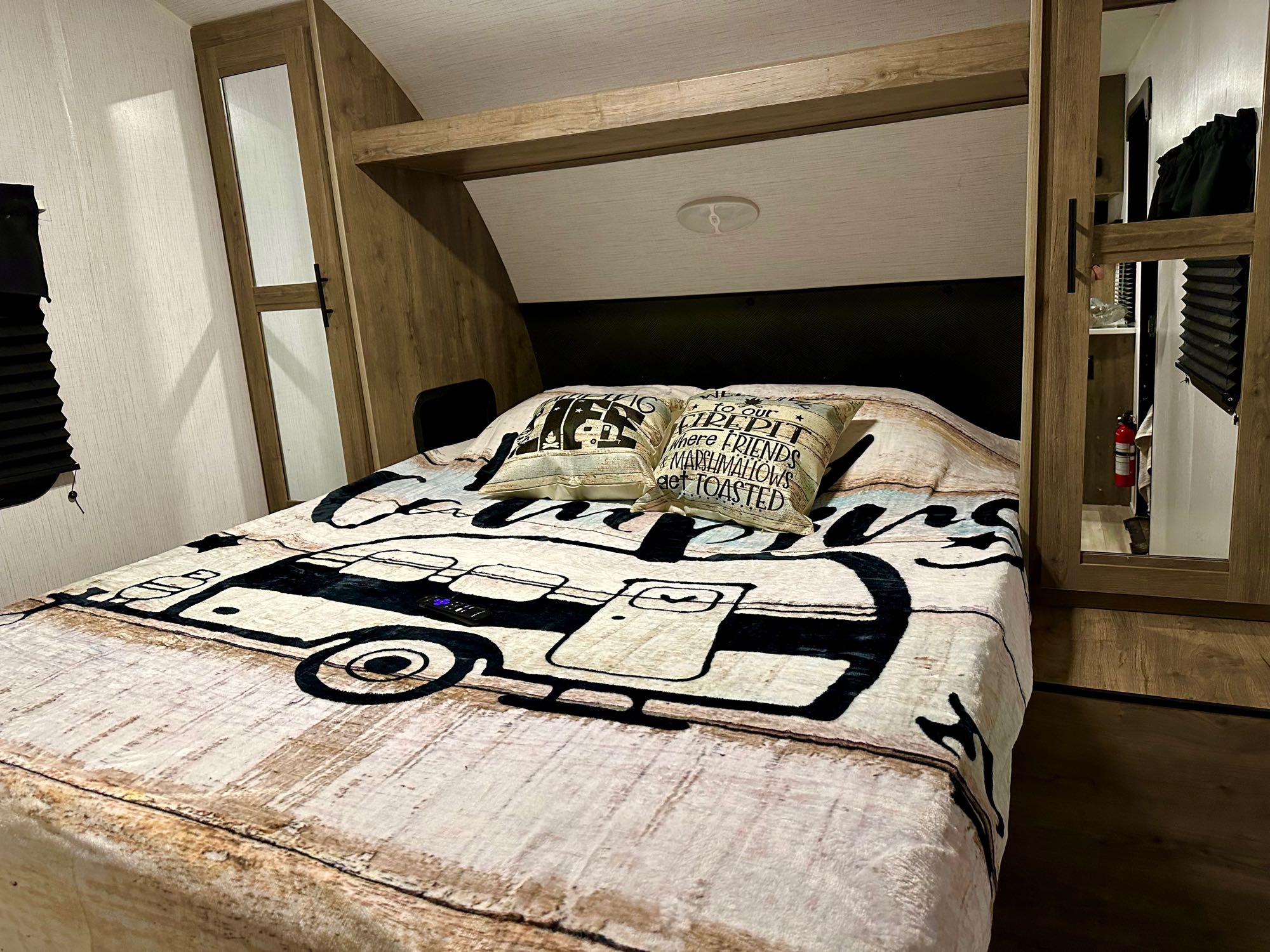 Cozy RV rental bedroom with camper-themed bedding, built-in storage, and warm overhead lighting.. Heartland Pioneer BH270 2023