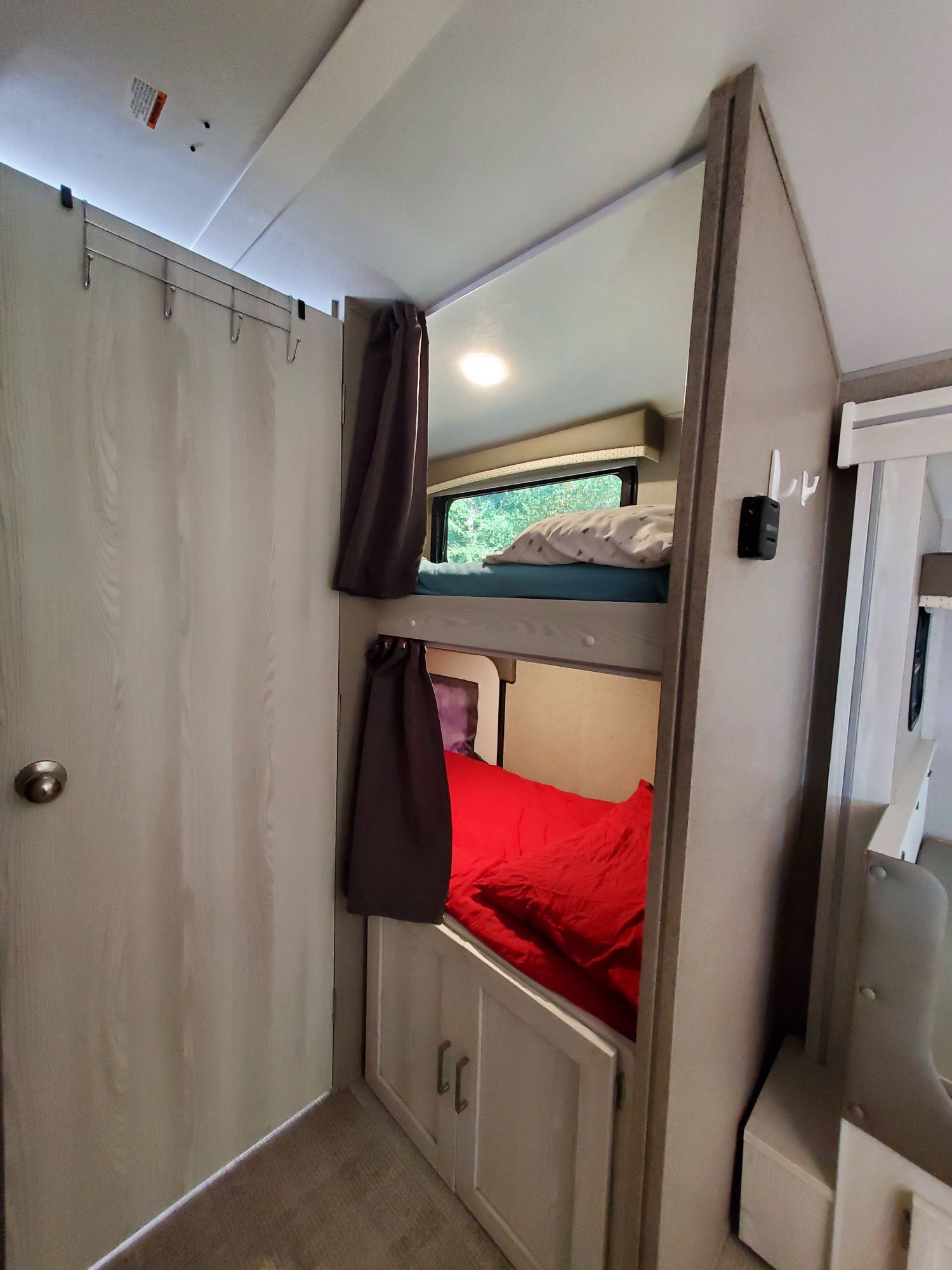 Cozy bunk beds inside this RV rental, featuring privacy curtains, a window view, and storage.. Forest River Rockwood Geo Pro 2020