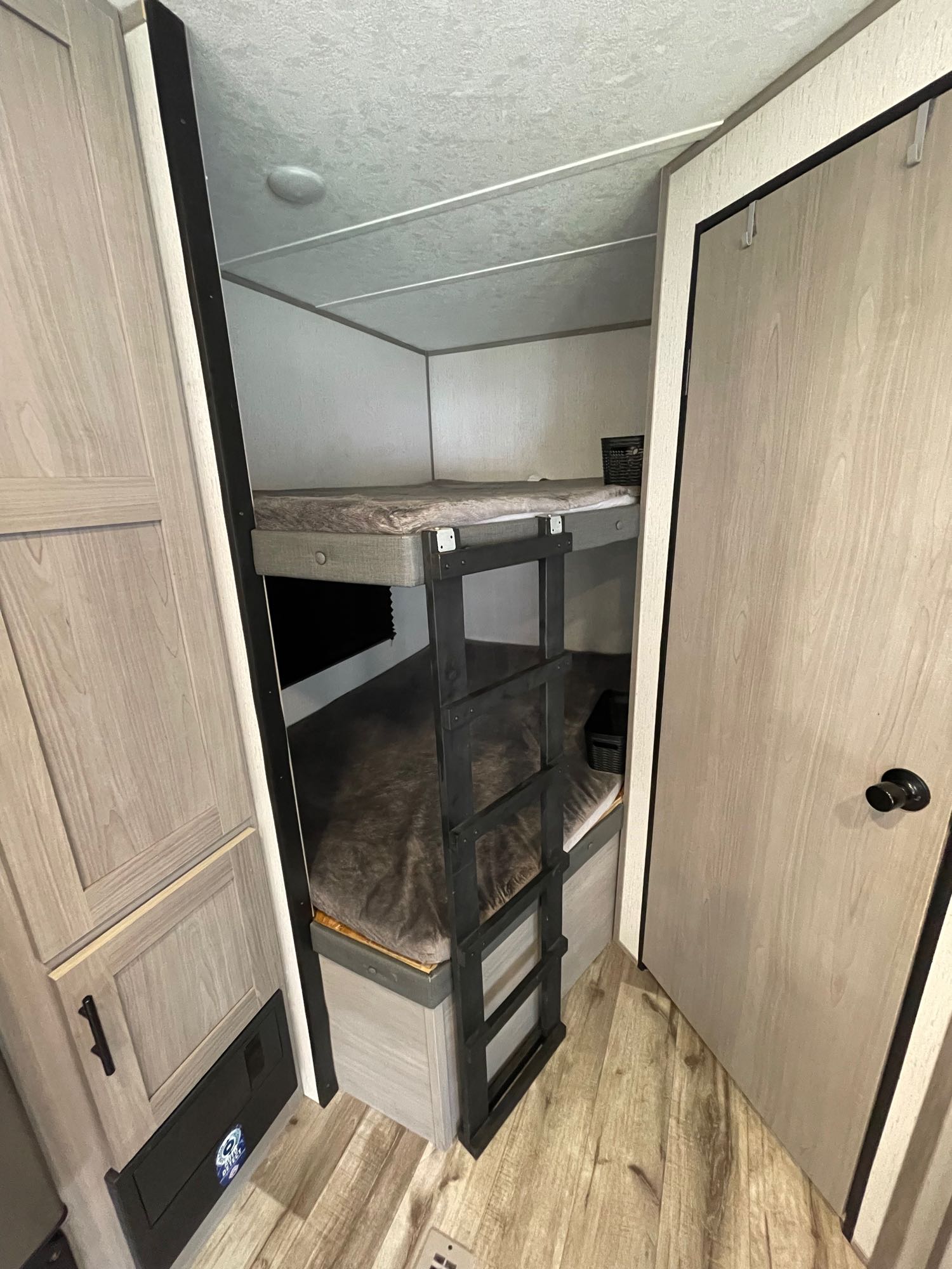 This RV rental features bunk beds with a ladder, providing a compact and comfortable sleeping area in a light-toned interior.. Coleman 263BH 2022