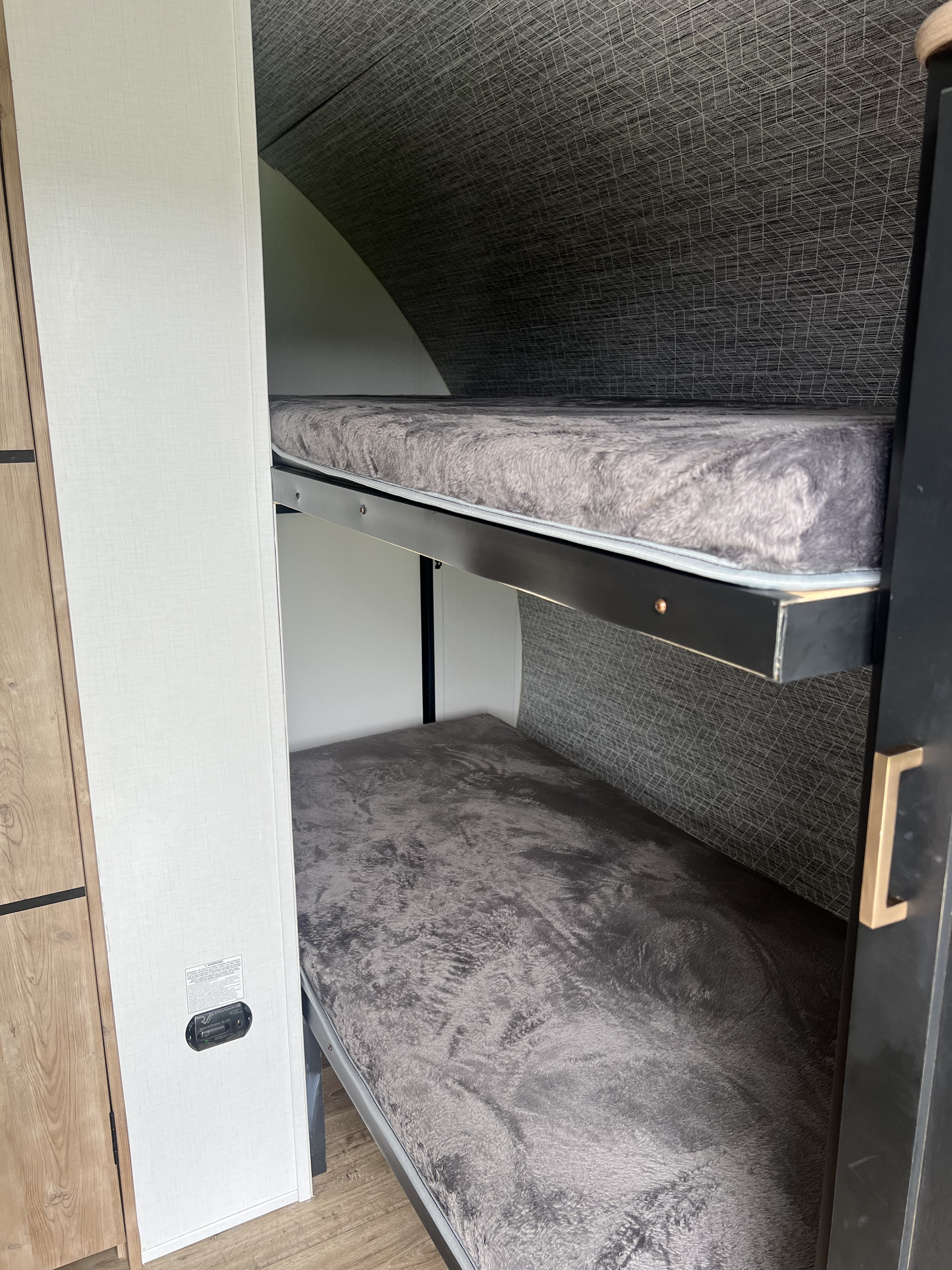 RV rental bunk beds: Cozy sleeping area with plush grey bedding inside a compact space.. Keystone RV Outback Ultra-Lite 2022