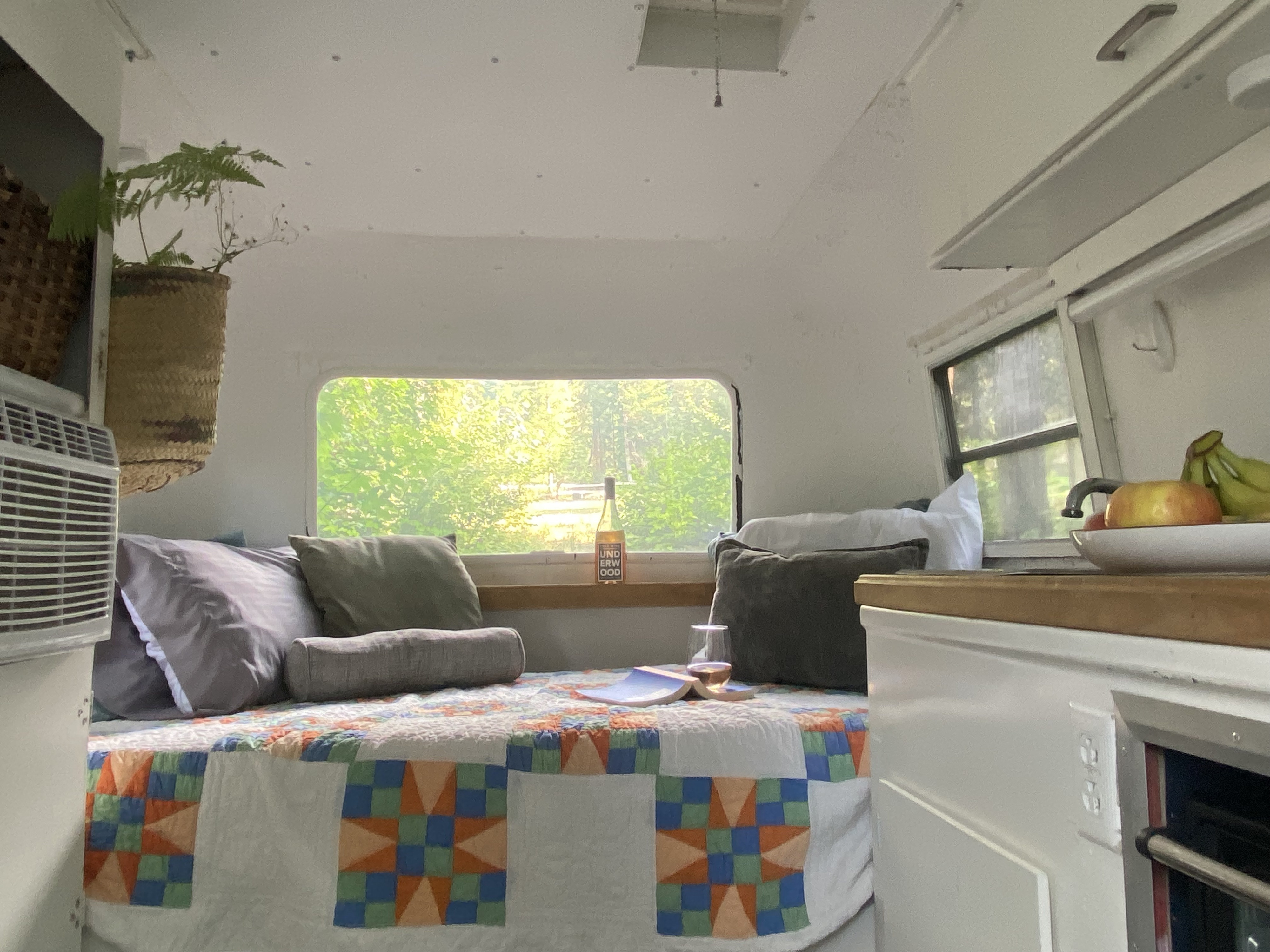 Cozy RV rental interior with a comfy bed, wine, a book, and a scenic nature view outside the window.. Boler American Wichita 1973