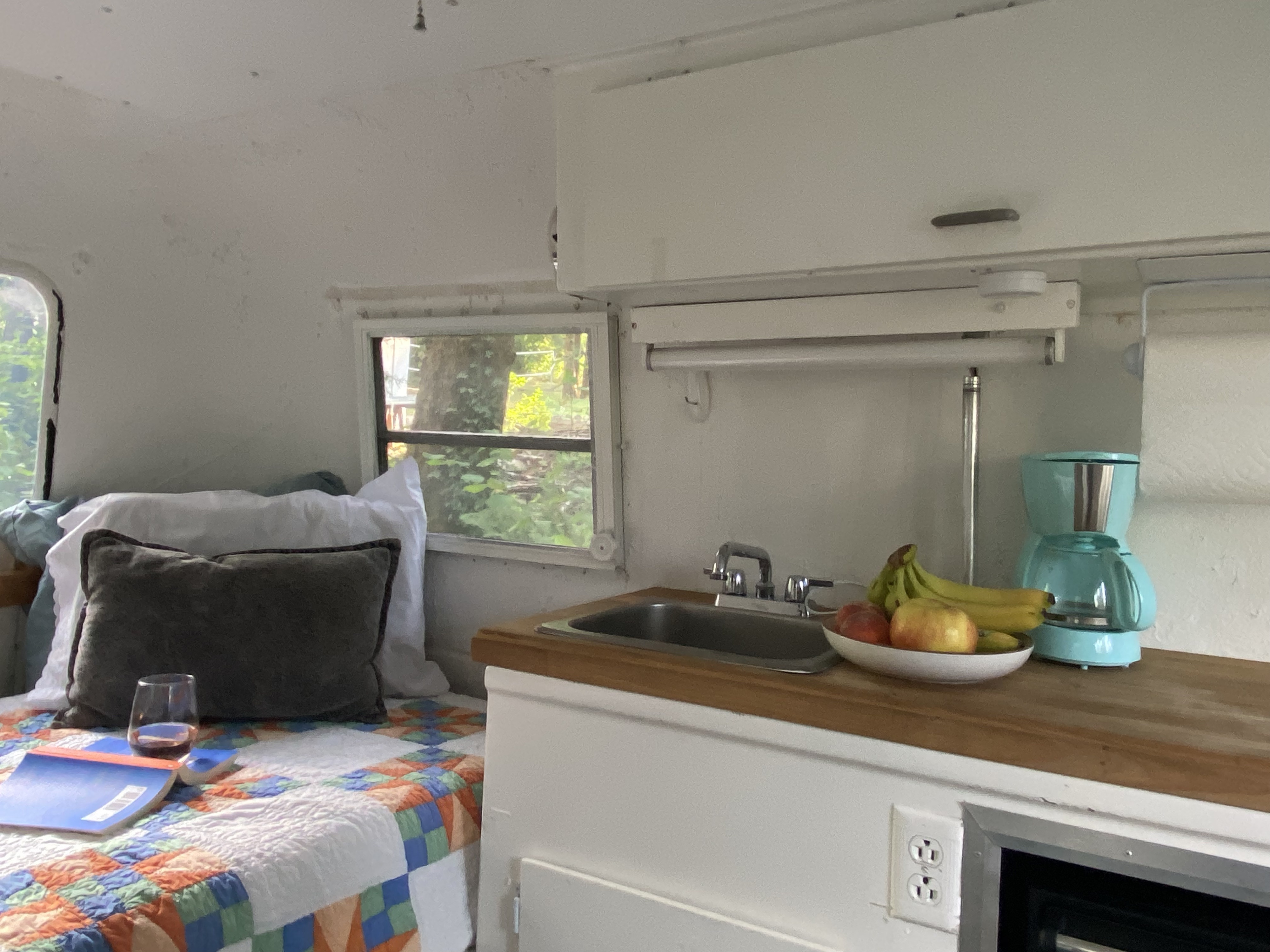 Inside an RV rental: a comfy bed, kitchen with fruit bowl, coffee maker, and natural light.. Boler American Wichita 1973