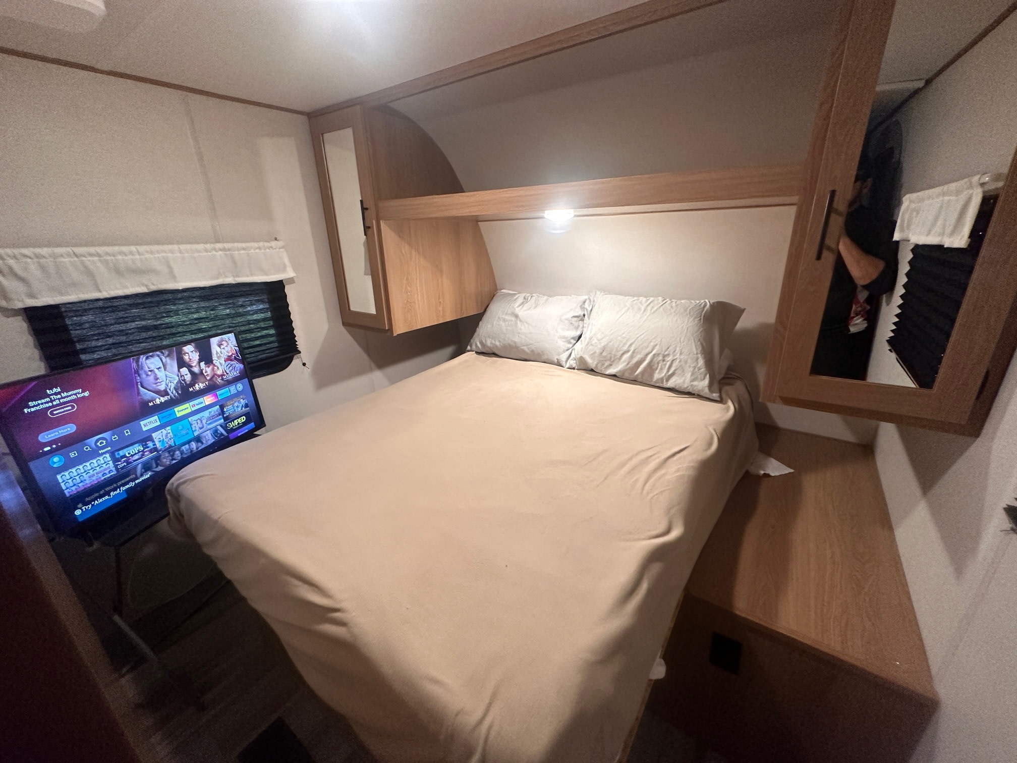 Cozy RV rental bedroom featuring a bed, streaming TV, and built-in storage. Perfect for a comfortable travel trailer getaway.. Forest River Avenger LE 2022