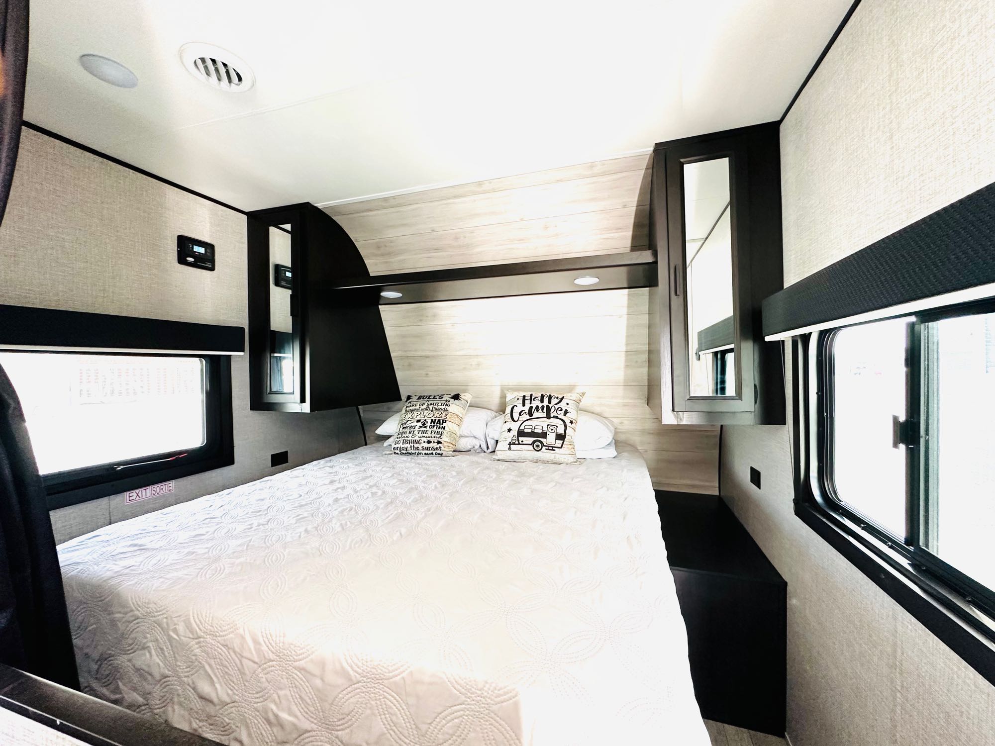 Inviting RV rental bedroom: cozy bed with decorative pillows, ample windows, and integrated storage for travelers.. Jayco Jay Flight SLX Rocky Mountain Edition 2021