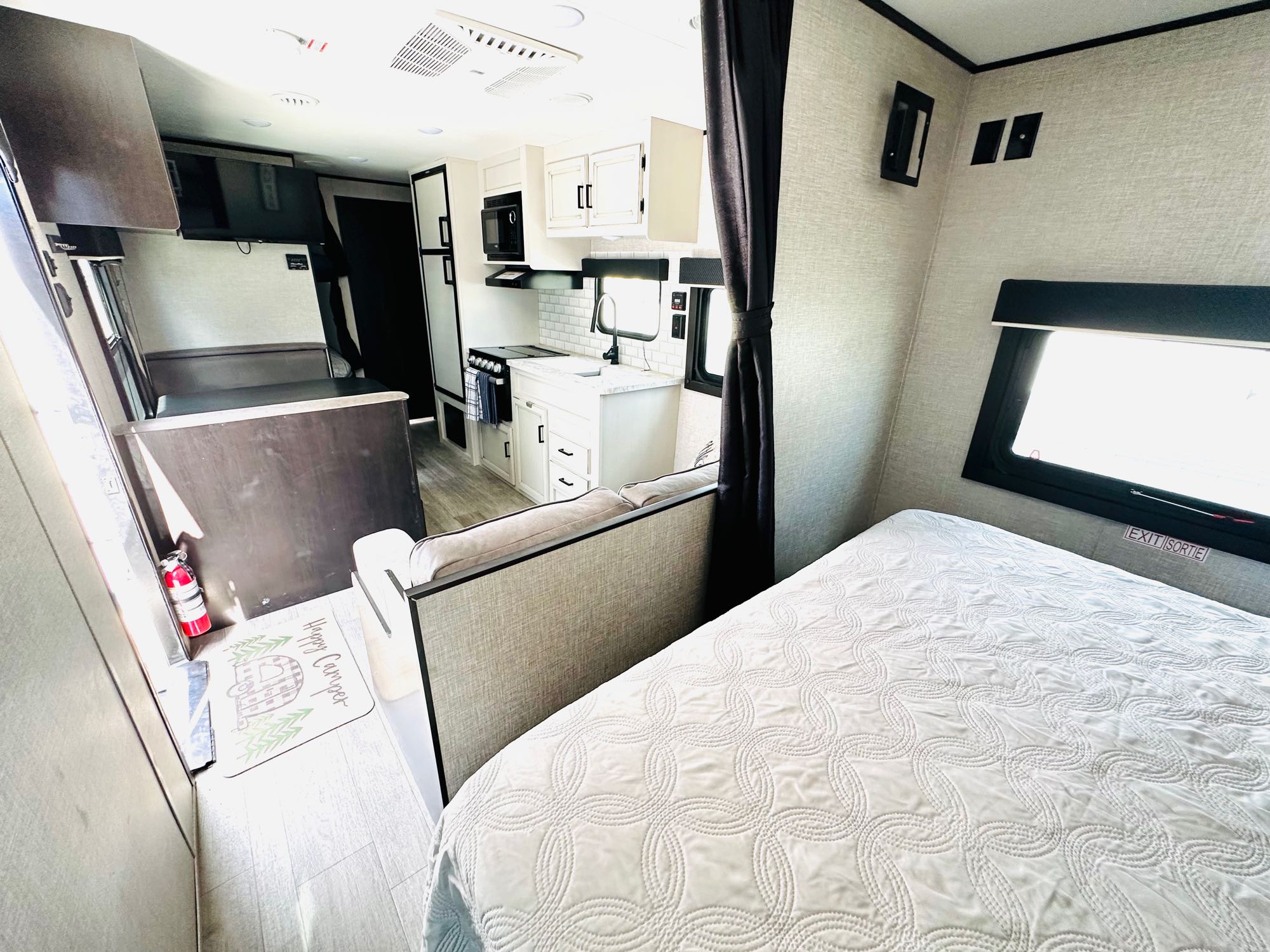 Inside this comfy rv rental: a pristine kitchen with white cabinets, a bed with a quilted comforter, and a spacious living area.. Jayco Jay Flight SLX Rocky Mountain Edition 2021