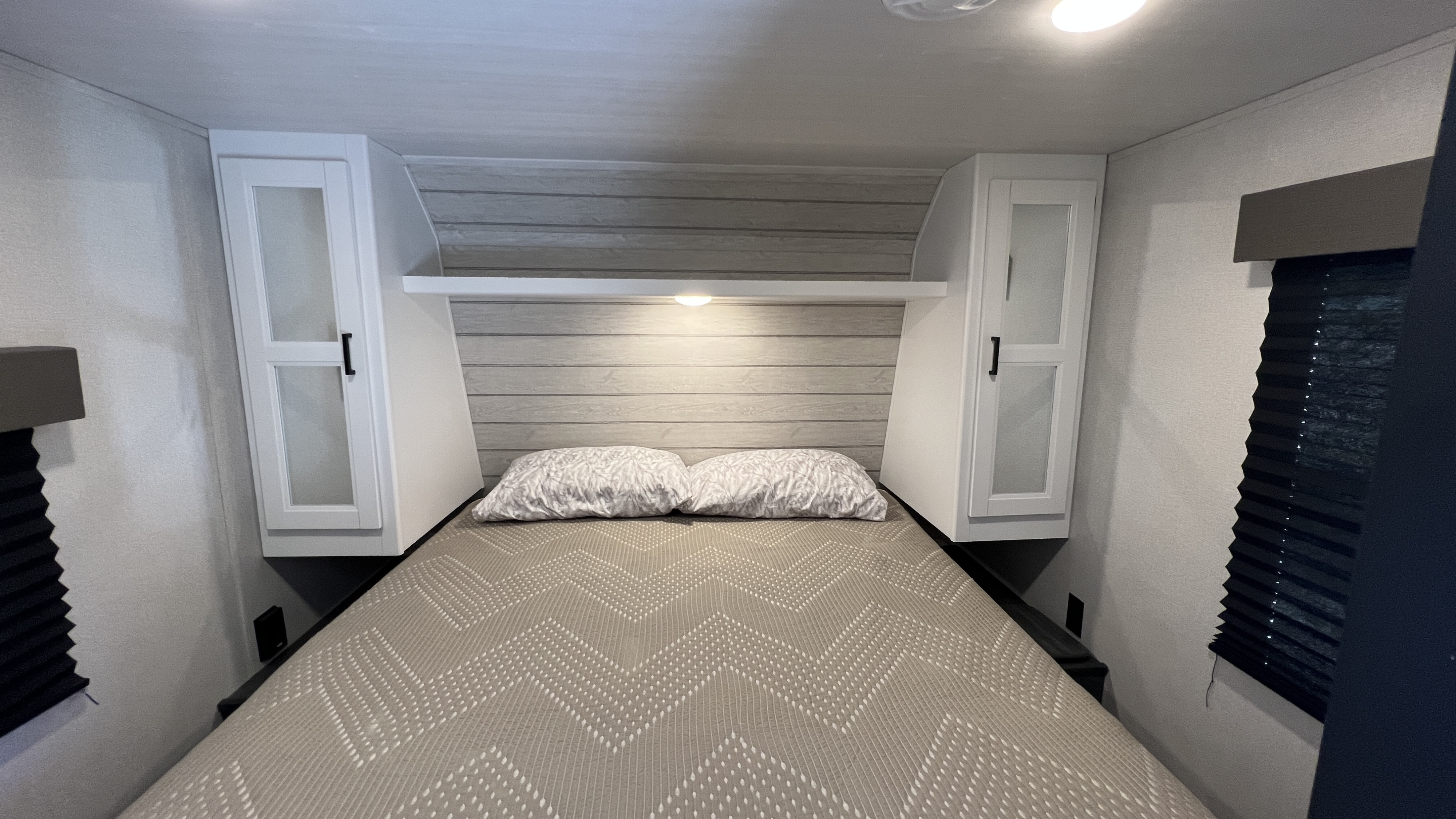 Cozy RV rental bedroom featuring a comfortable bed, overhead storage, and ambient lighting, perfect for travel.. Keystone RV Hideout 2022