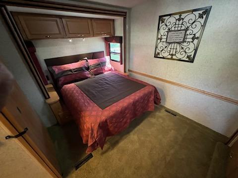 This RV rental features a cozy bedroom with a large bed, overhead cabinets, and decorative wall art. Perfect for your next adventure.. Itasca Sunrise 2008