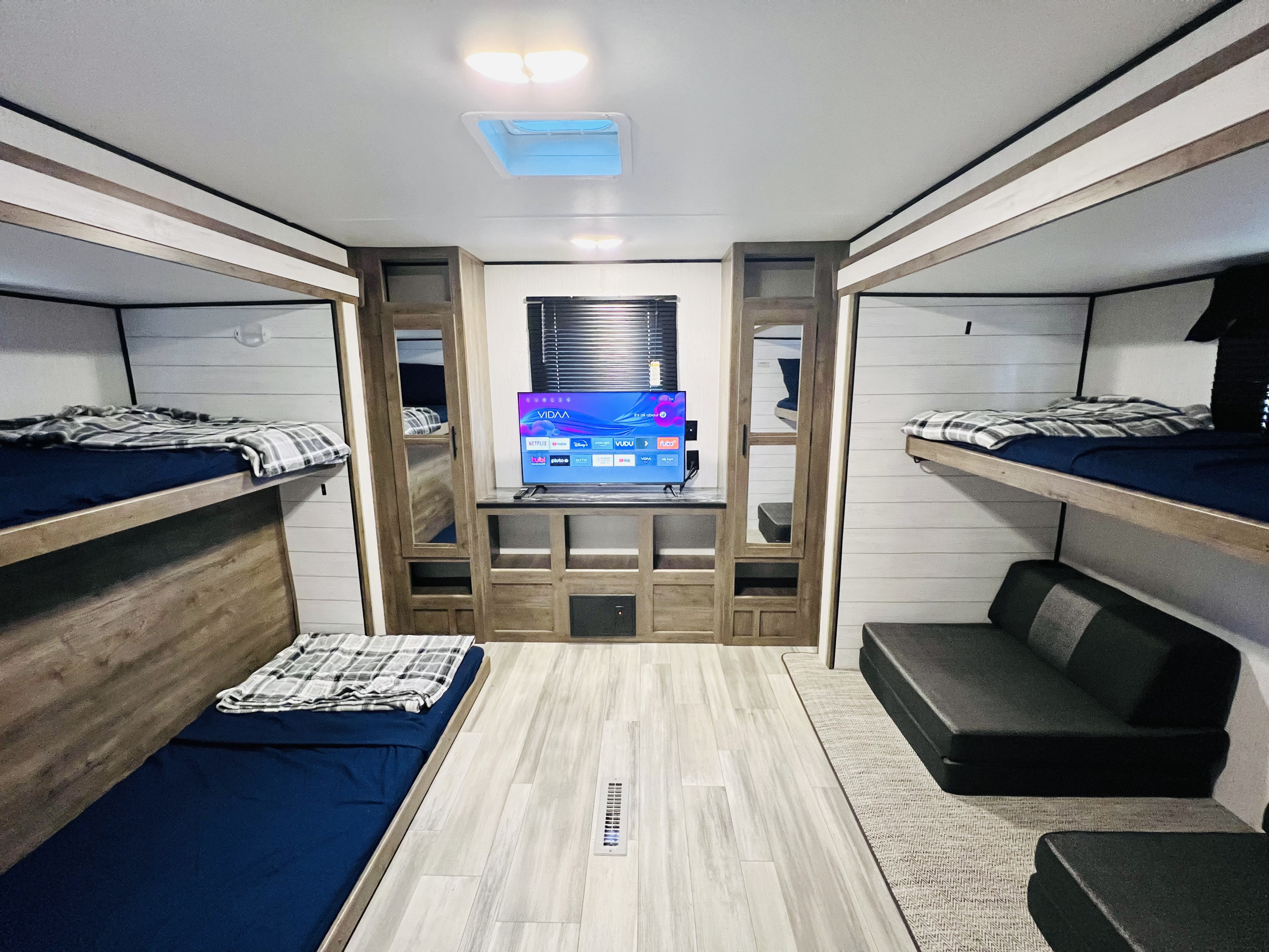 Bright RV rental interior with bunk beds, TV display, light wood cabinetry, and sleek flooring.. Heartland RVs Pioneer 2022
