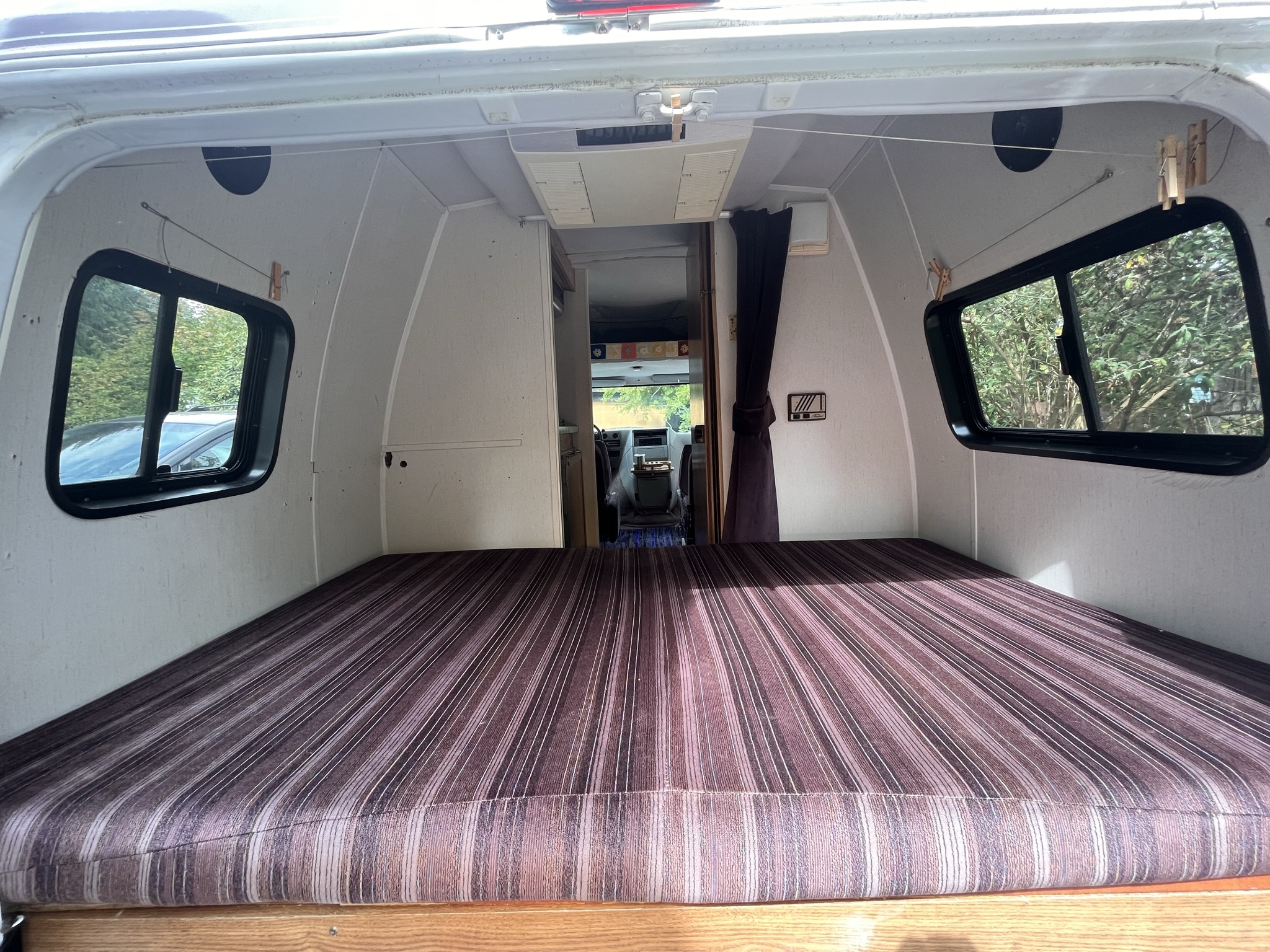 Experience comfort in this RV rental! View of the rear sleeping area with striped mattress, side windows, and forward to the cab.. Horizon G20 1994