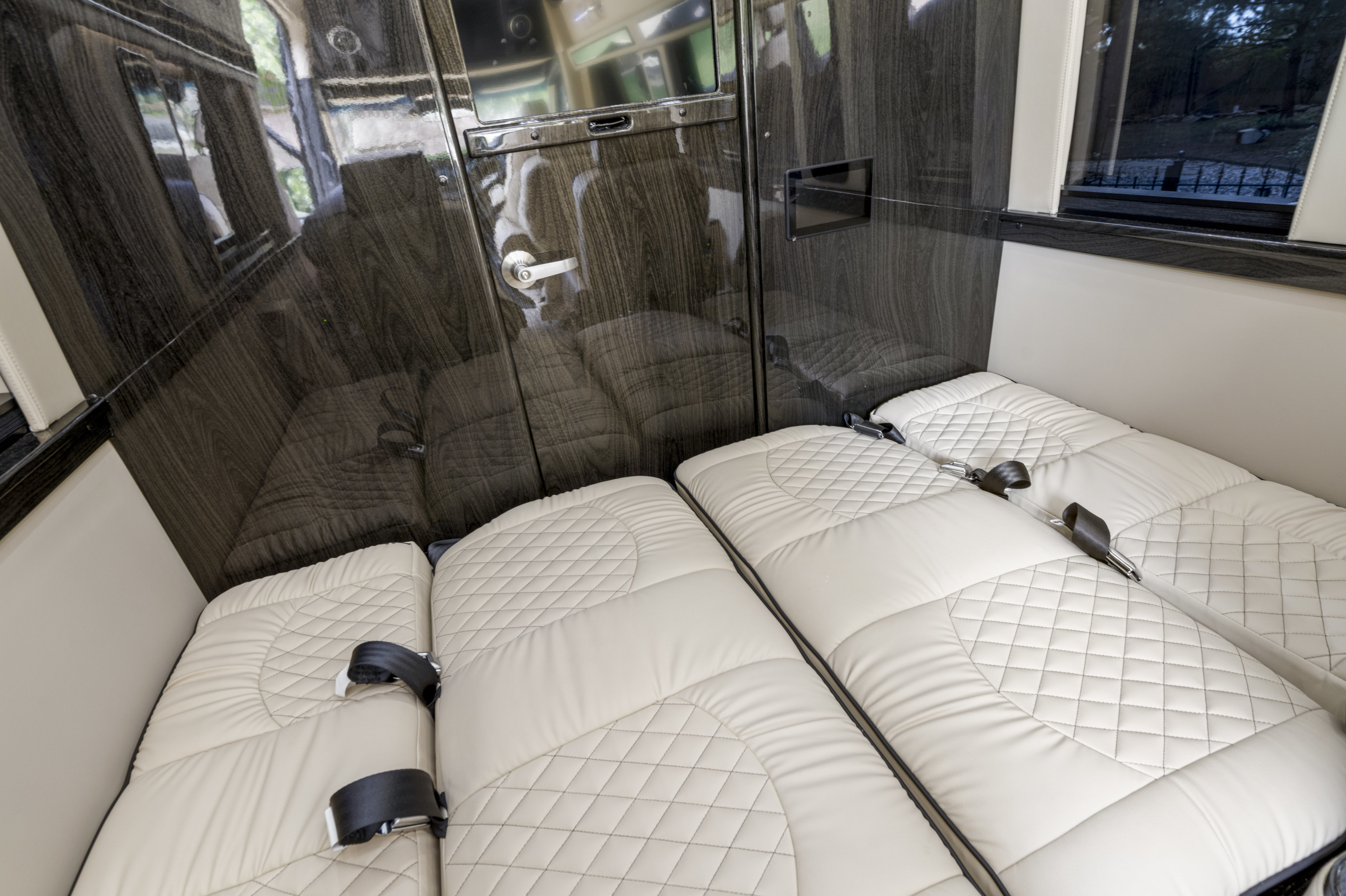 RV rental comfort: interior features plush, quilted seating that converts to beds, glossy wood accents, & window views.. Ultimate Toys Ultimate Coach 2024