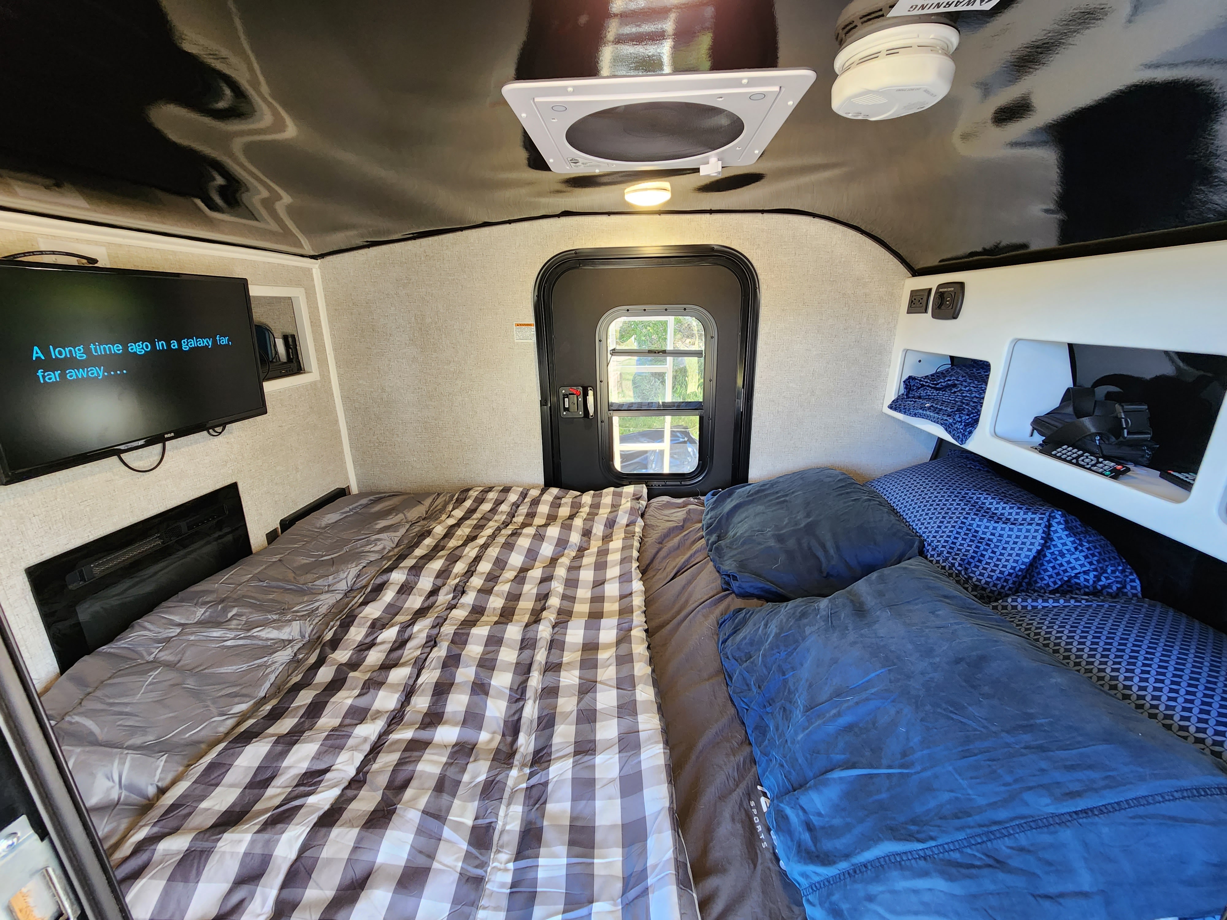 Cozy rv rental interior featuring a comfortable bed, TV showing Star Wars, and functional storage.. Modern Buggy Little Buggy 10LR 2024