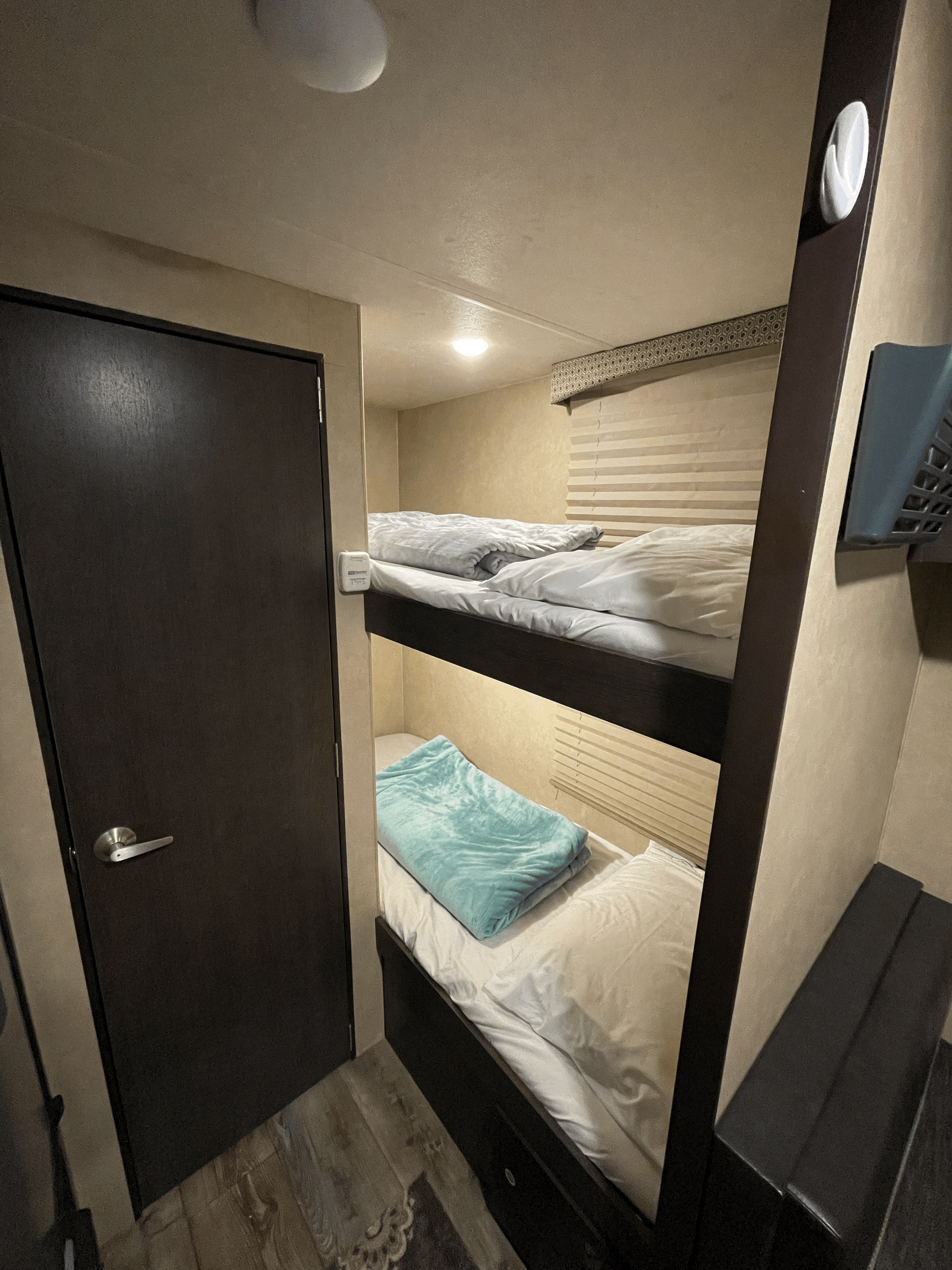 Inside an RV rental: a cozy bunk bed setup with soft bedding, a privacy door, and window blinds, perfect for travel.. Forest River Sonoma 2019
