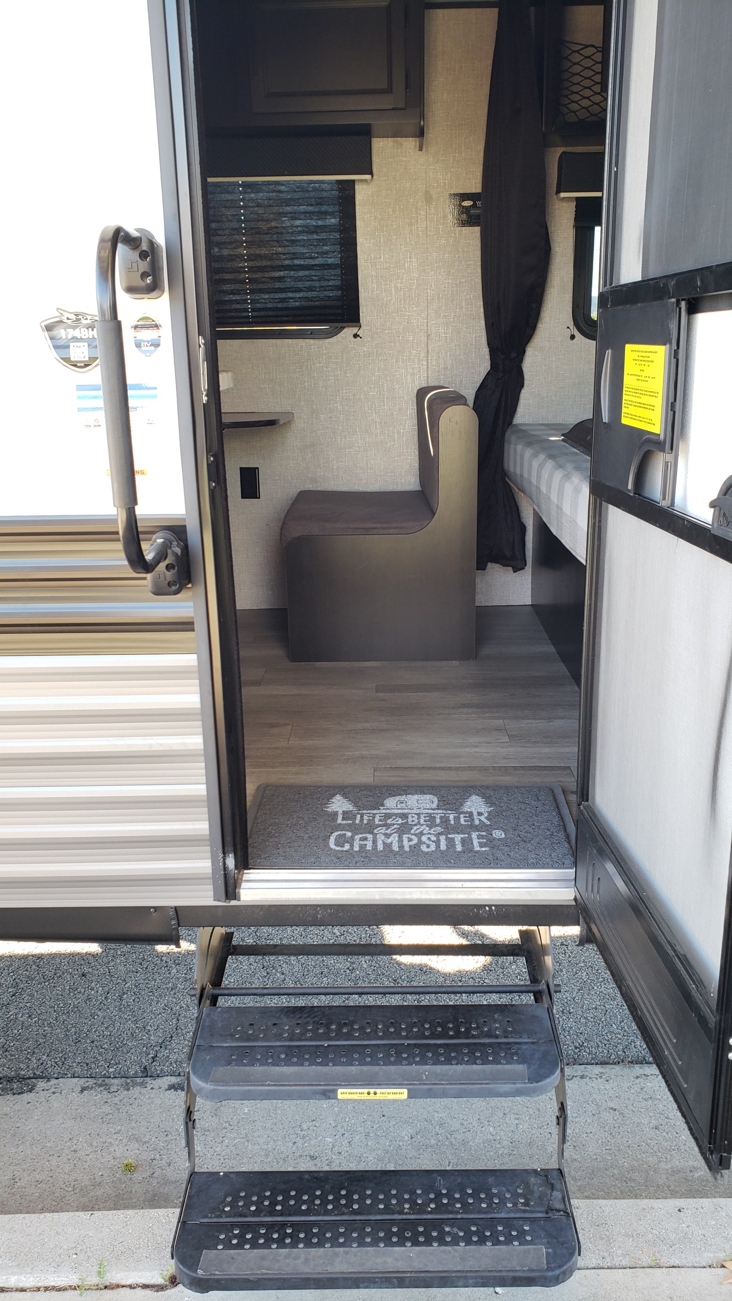 An inviting view into an RV rental, showcasing its compact interior with a dinette, bed, and entry steps.. Jayco Jay Flight SLX Baja Edition 2022