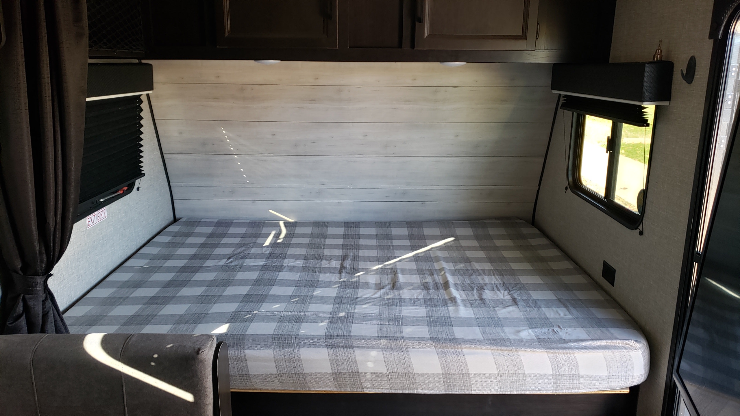 Cozy RV rental bedroom featuring a grey plaid bed, light wood-paneled walls, and windows for compact travel comfort.. Jayco Jay Flight SLX Baja Edition 2022