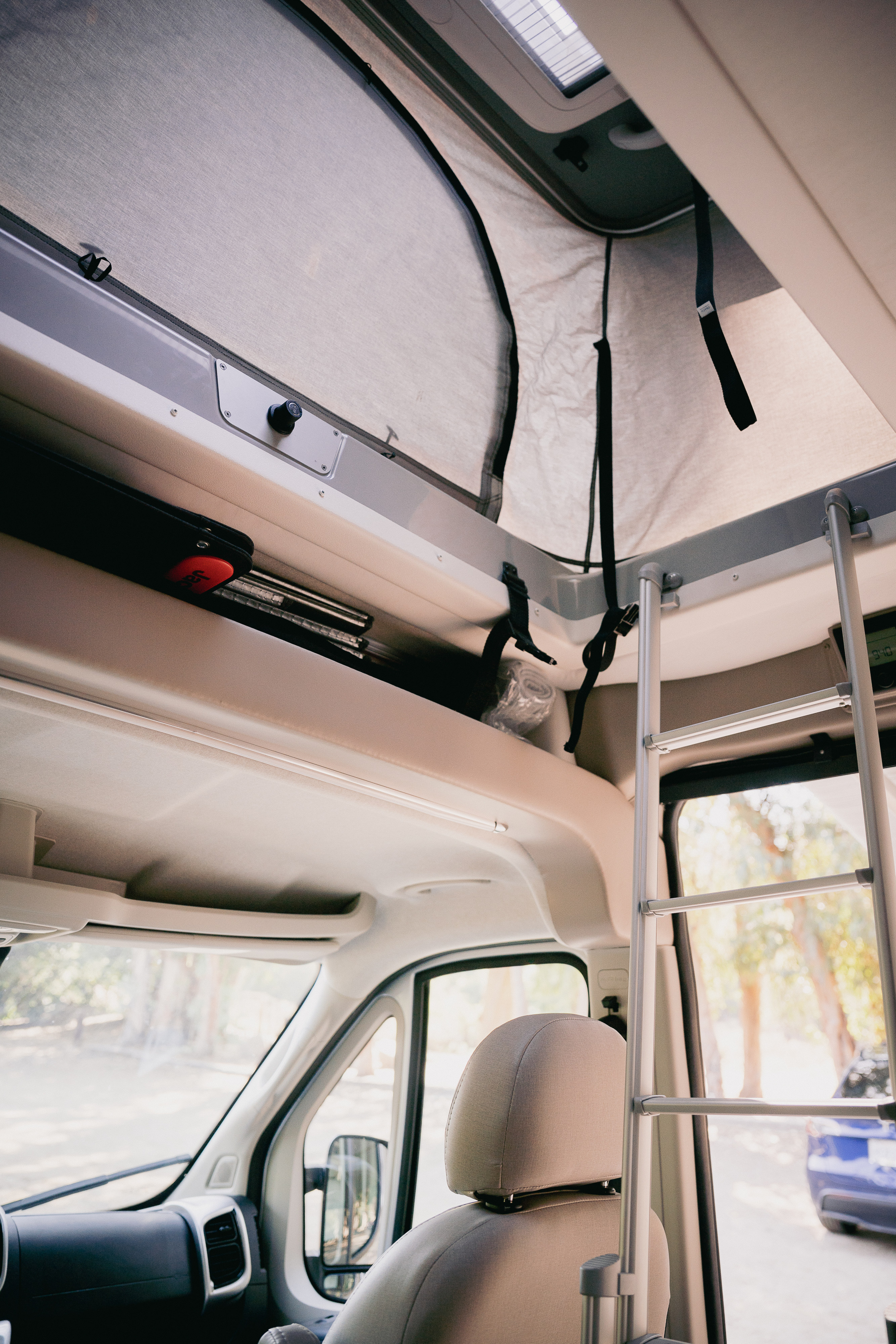 RV rental interior: over-cab sleeping area with fabric walls, access ladder, and front cabin storage.. Thor Sequnce 2023