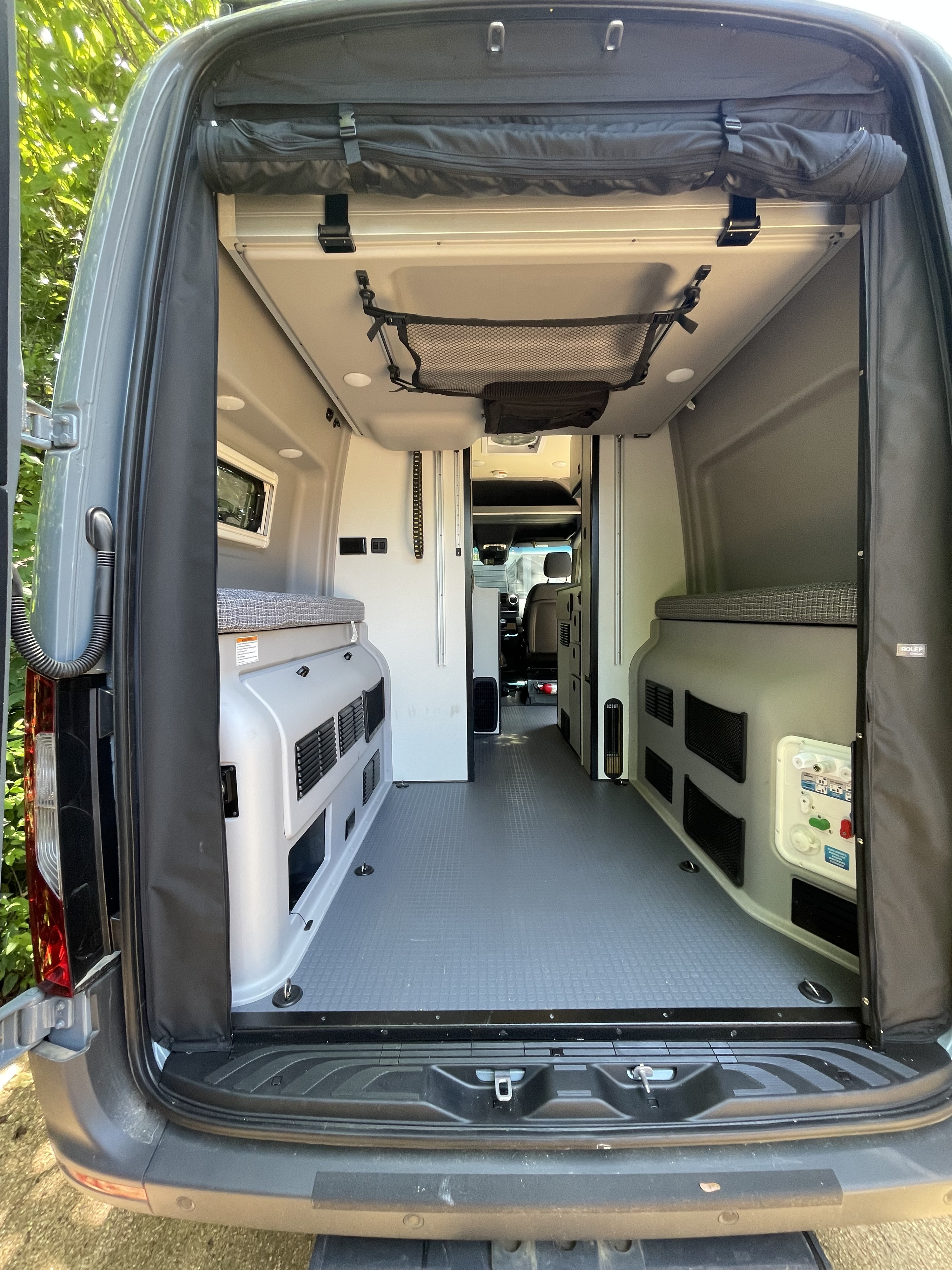 Clean, spacious rv rental camper van interior. Rear view showing beds & aisle, perfect for travel.. Winnebago Revel 2023