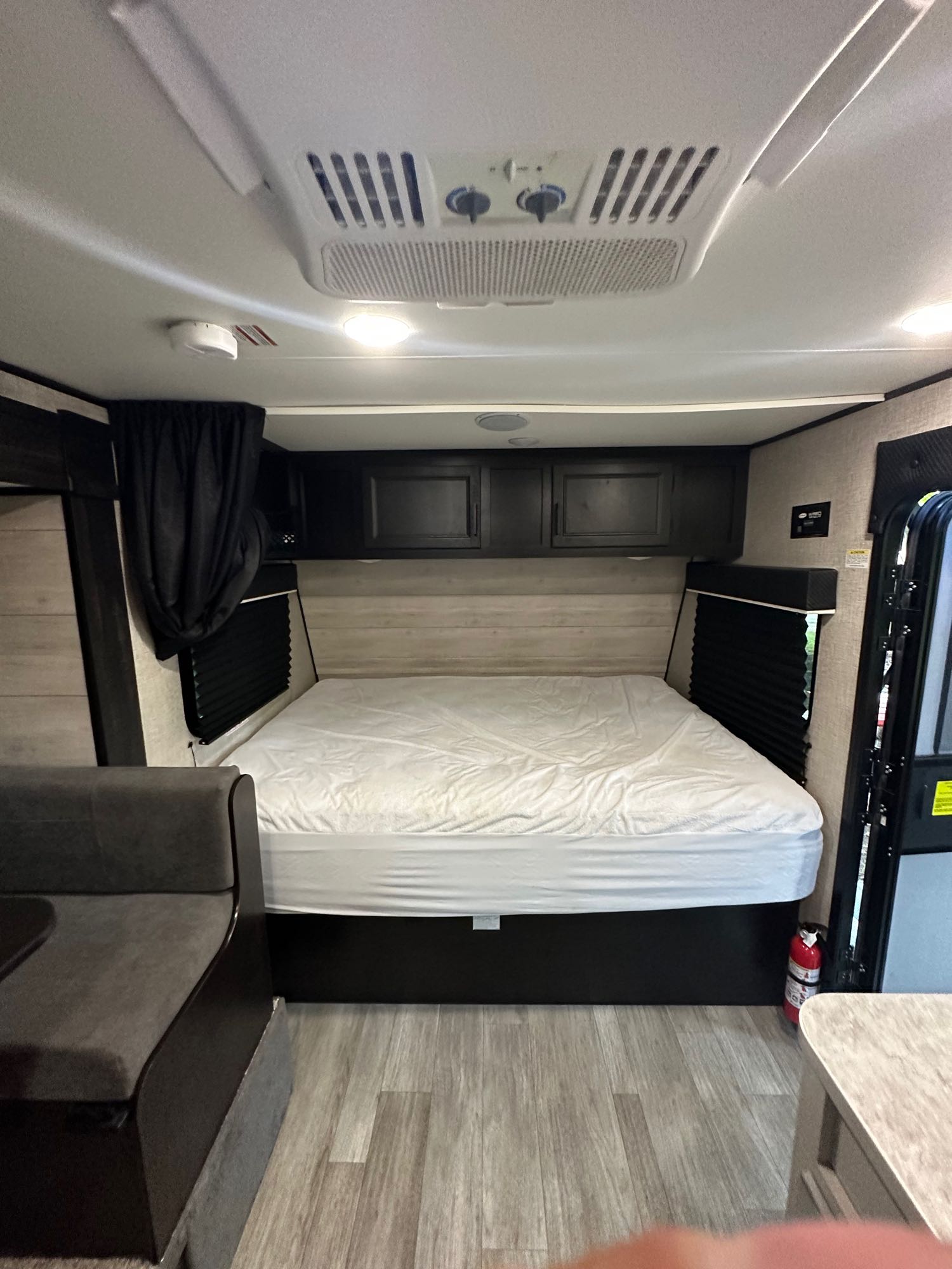 Inside an RV rental: cozy bedroom area with a queen bed, overhead storage, and dinette seating. AC unit on ceiling.. Jayco Jay Flight SLX7 184bs 2022
