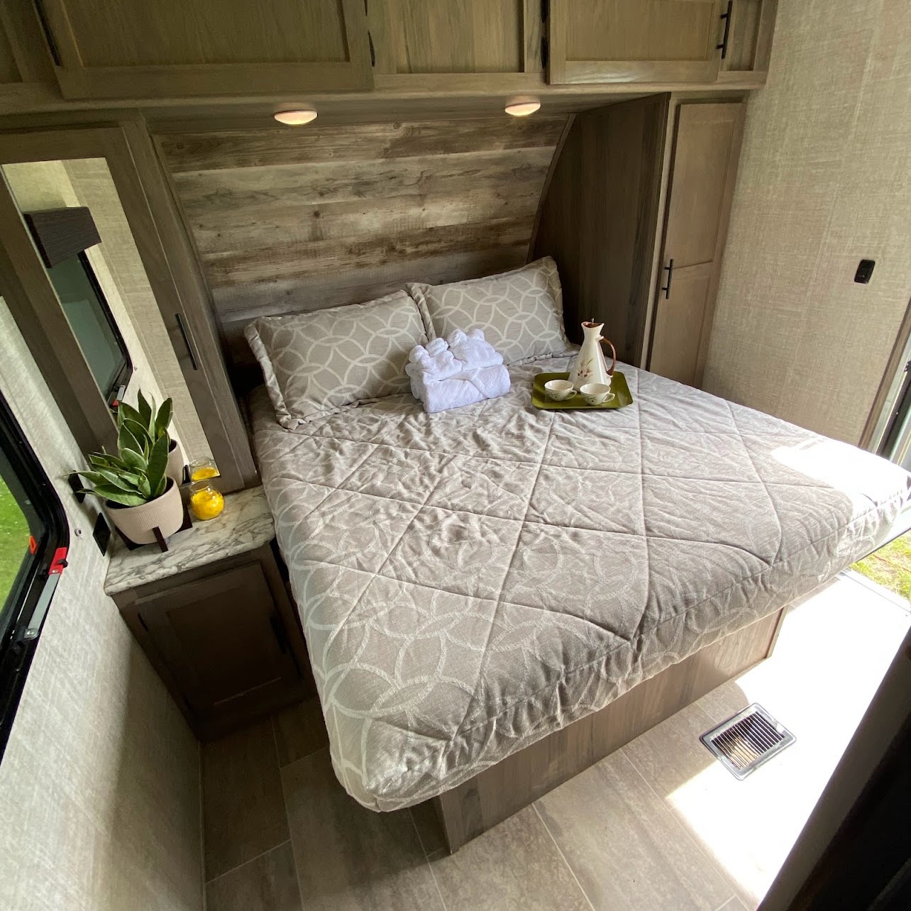 Inside your RV rental: a modern, cozy bedroom with comfortable bed, patterned linens, fresh towels, and a plant for comfort.. Gulf Stream Conquest 2021