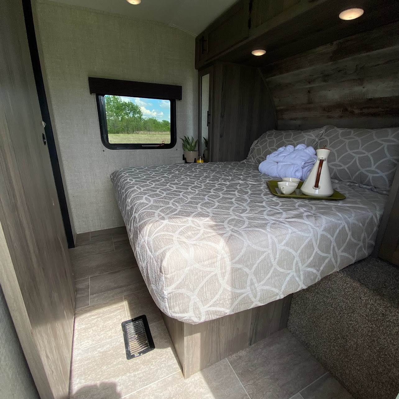Relax in this comfortable RV rental bedroom. Features include patterned bedding, a nature view from the window, and cozy amenities.. Gulf Stream Conquest 2021