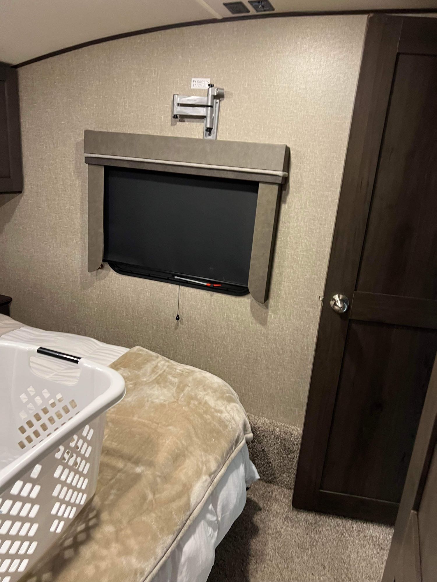 This RV rental bedroom offers a wall-mounted TV, comfy bed, and a laundry basket for convenience.. Grand Design Reflection 2021
