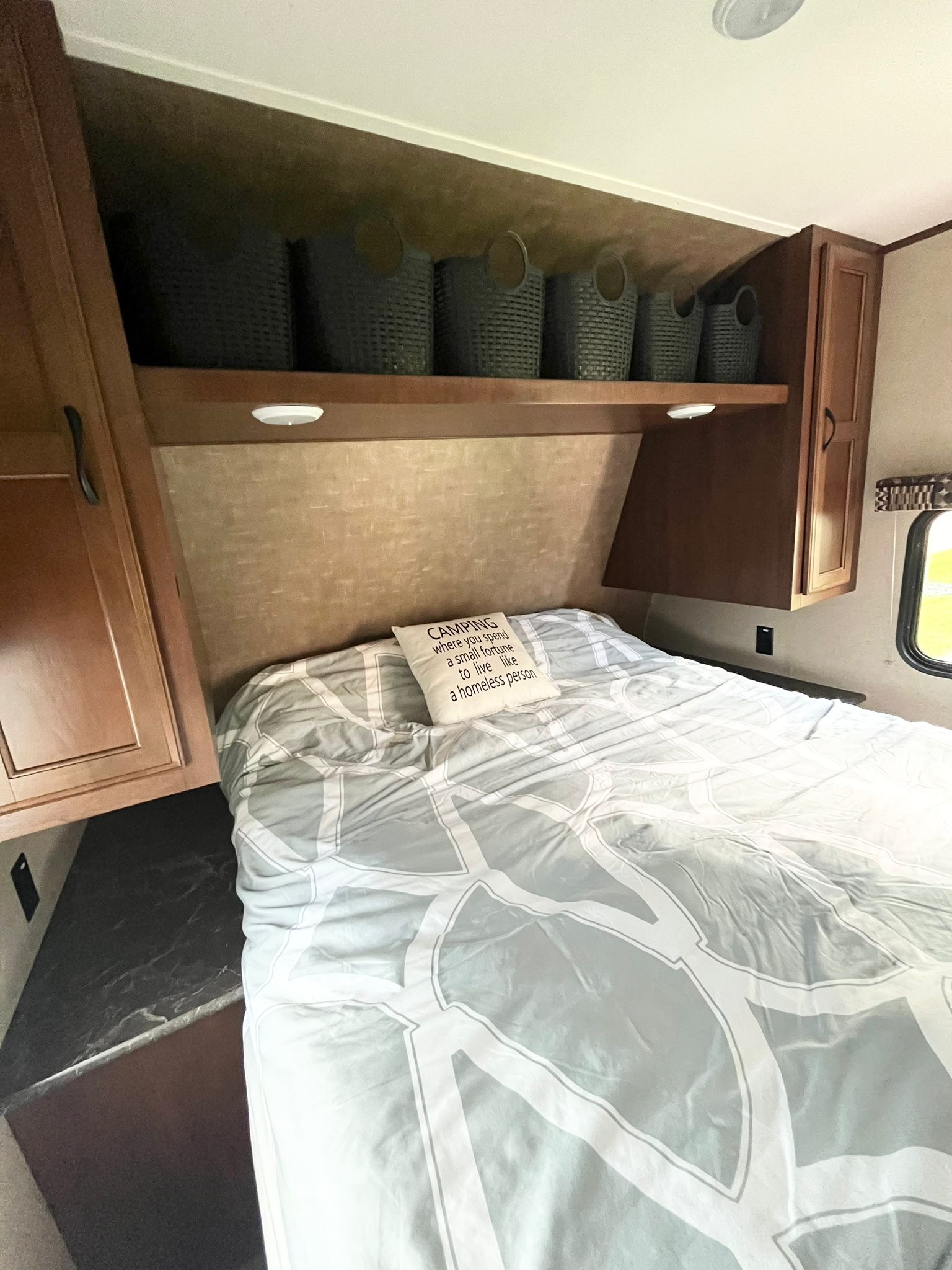 Cozy RV rental bedroom with patterned bedding, convenient overhead storage baskets, and rich wood cabinets.. Jayco Jay Flight SLX 2016