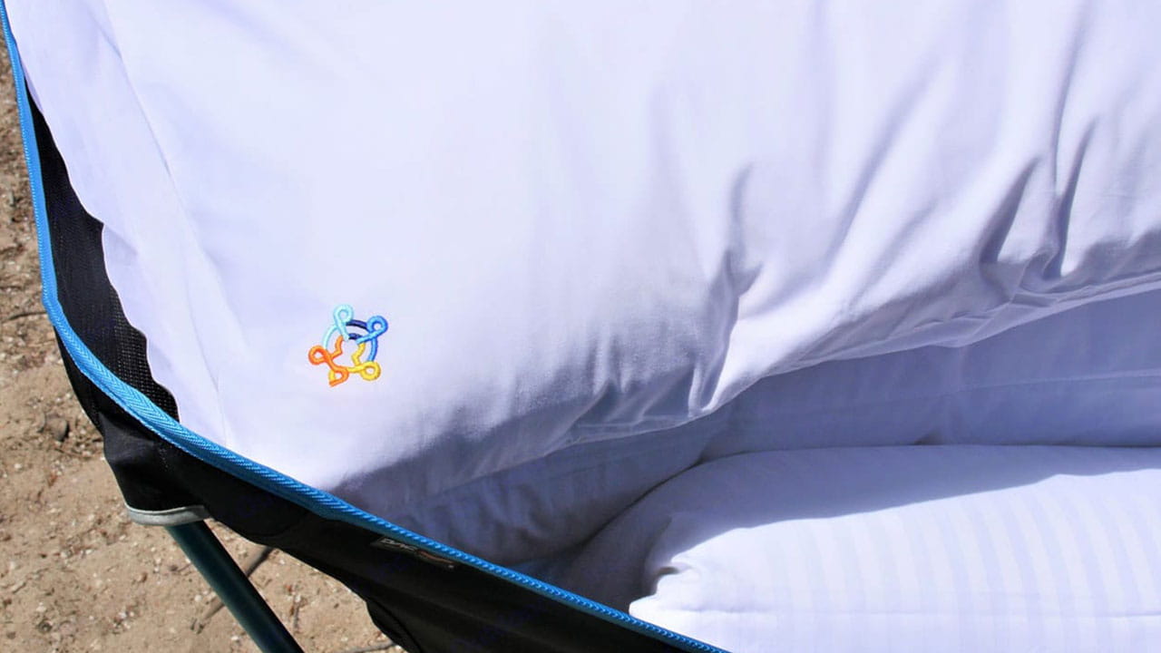 A plush white pillow with a colorful logo, providing cozy comfort for your RV rental adventures. Includes striped bedding.. Isuzu D-max Double Cab 2020