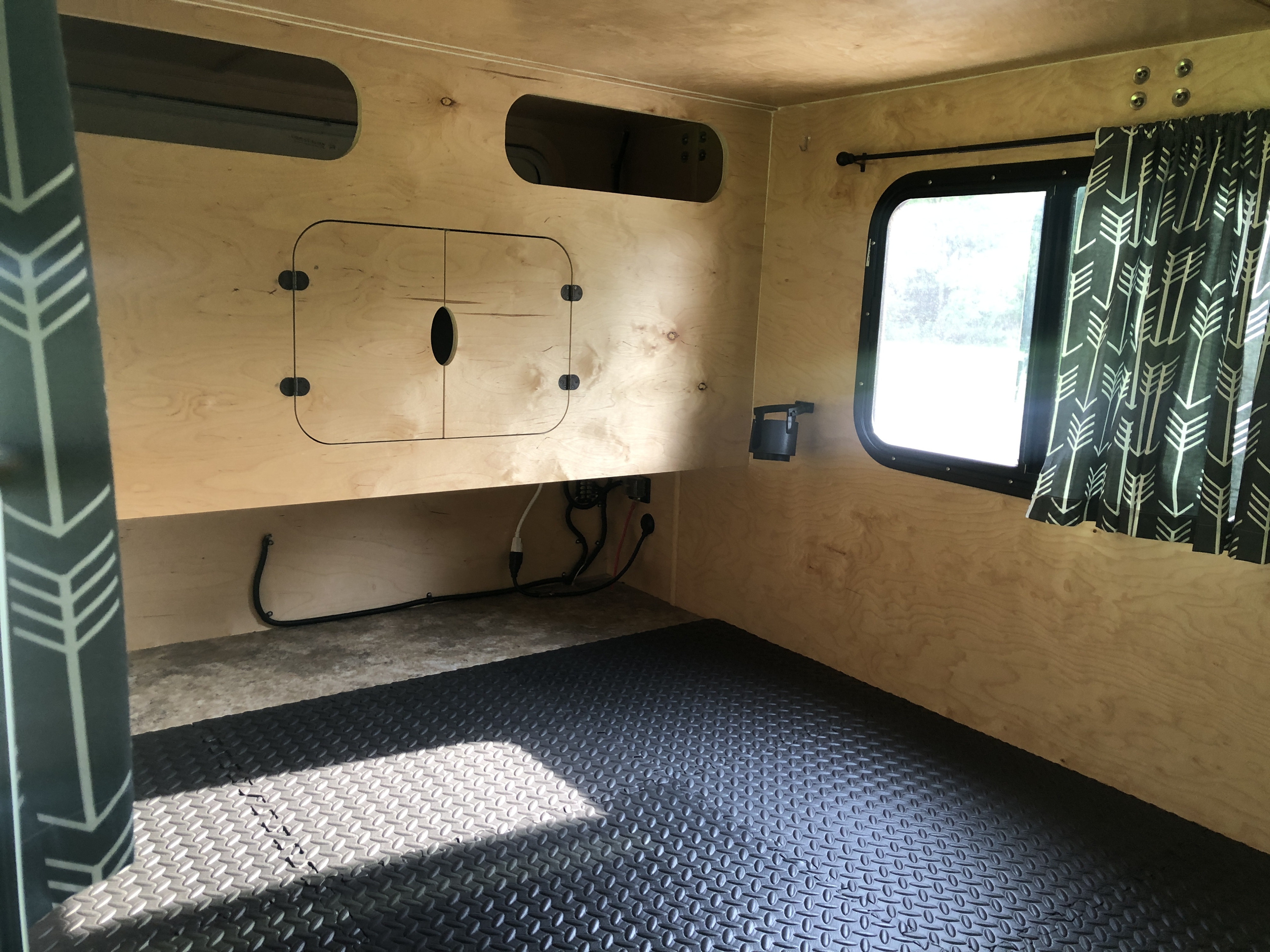 Cozy RV rental interior with light wood walls, built-in storage, a patterned window curtain, and rubber floor mats.. Hiker Trailer Highway Deluxe 2020